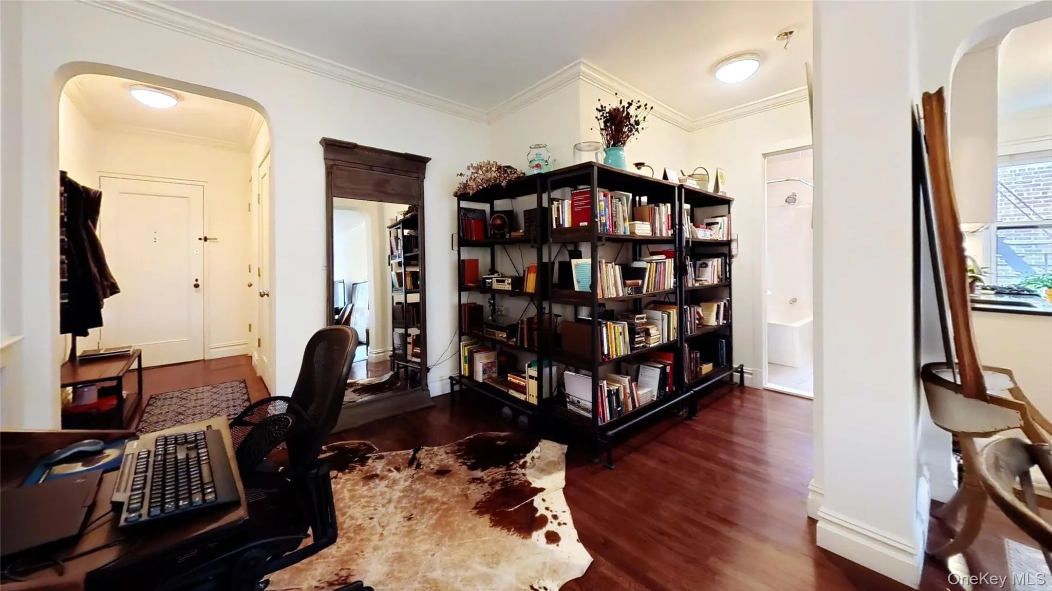 Home office featuring arched walkways, ornamental molding, and dark wood finished floors Home office featuring arched walkways, ornamental molding, and dark wood finished floors