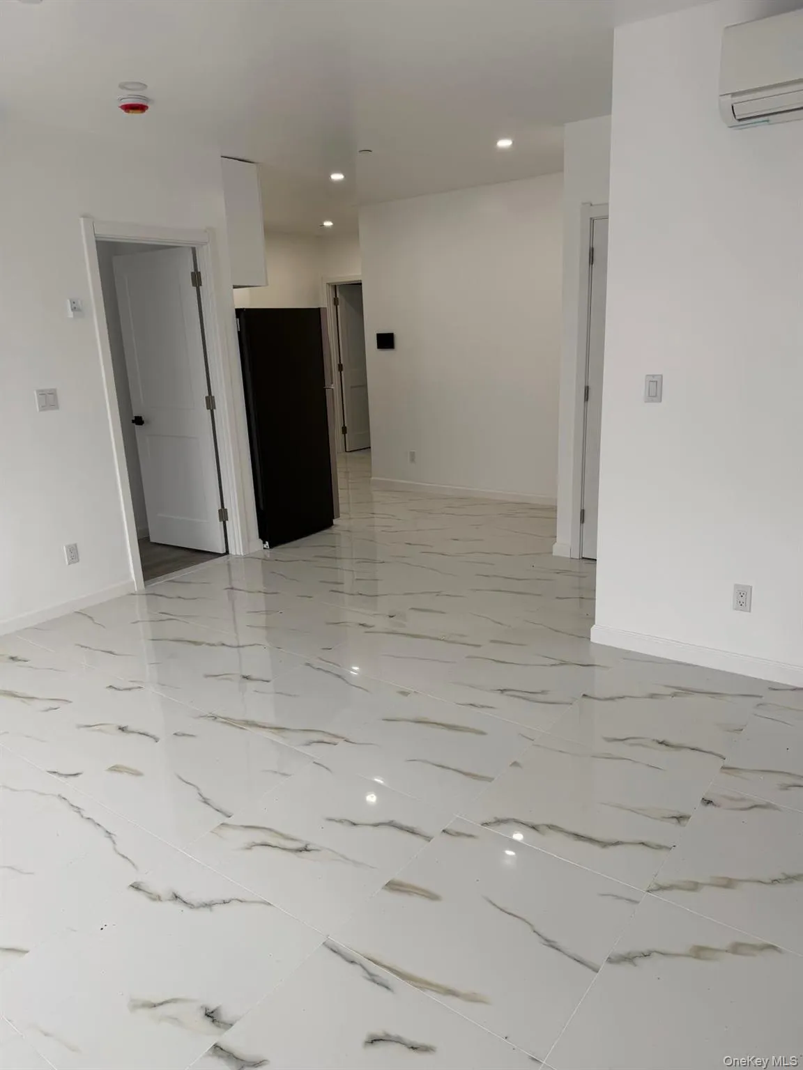 Unfurnished room with recessed lighting, a wall mounted air conditioner, and light marble finish flooring Unfurnished room with recessed lighting, a wall mounted air conditioner, and light marble finish flooring