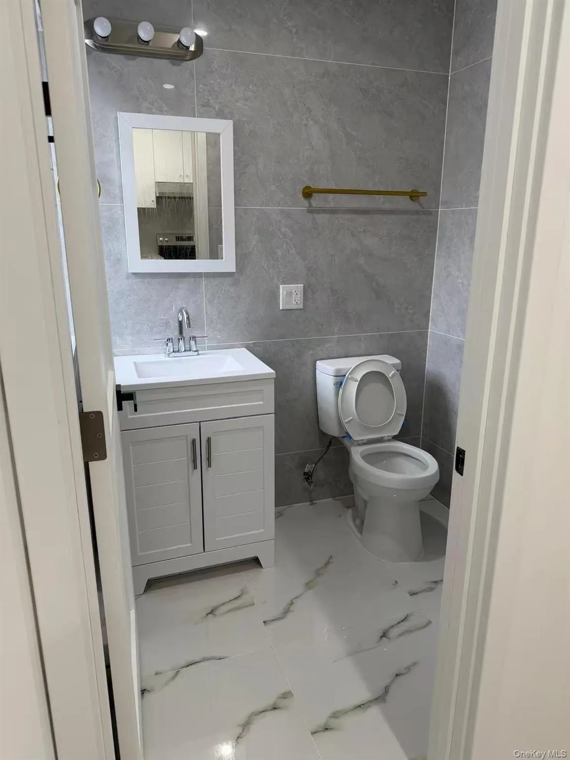 Half bath featuring vanity, tile walls, and light marble finish flooring Half bath featuring vanity, tile walls, and light marble finish flooring