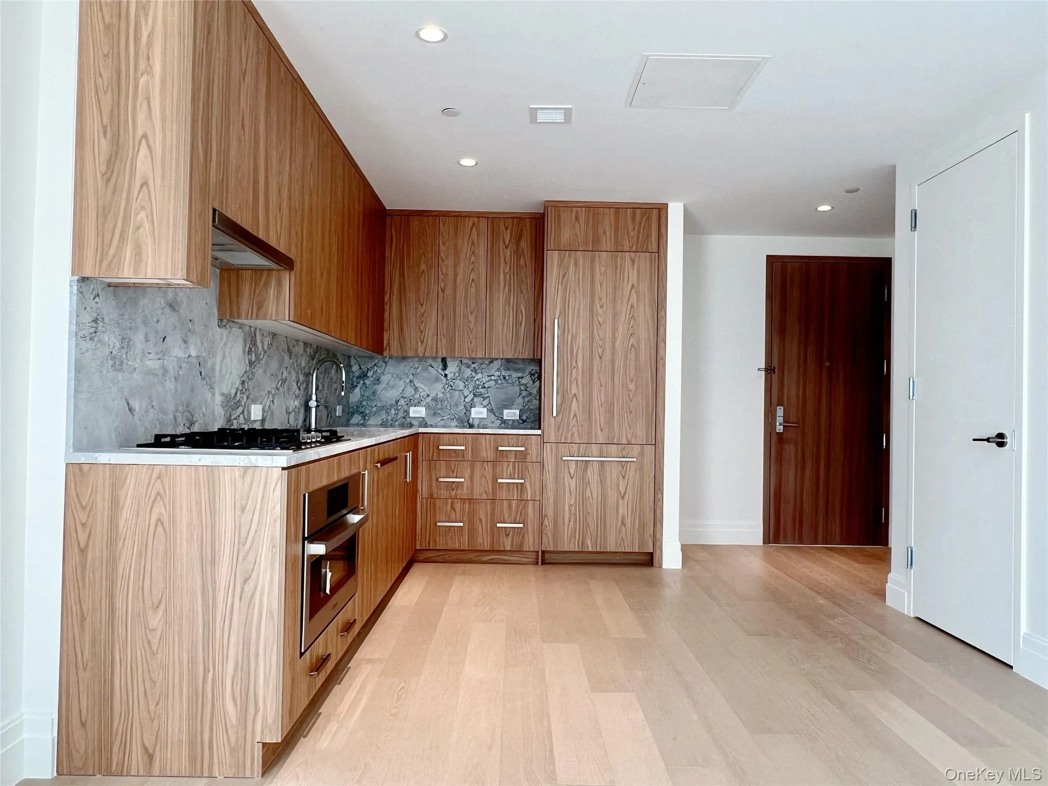 Kitchen featuring modern cabinets, appliances with stainless steel finishes, light stone counters, recessed lighting, and custom range hood Kitchen featuring modern cabinets, appliances with stainless steel finishes, light stone counters, recessed lighting, and custom range hood