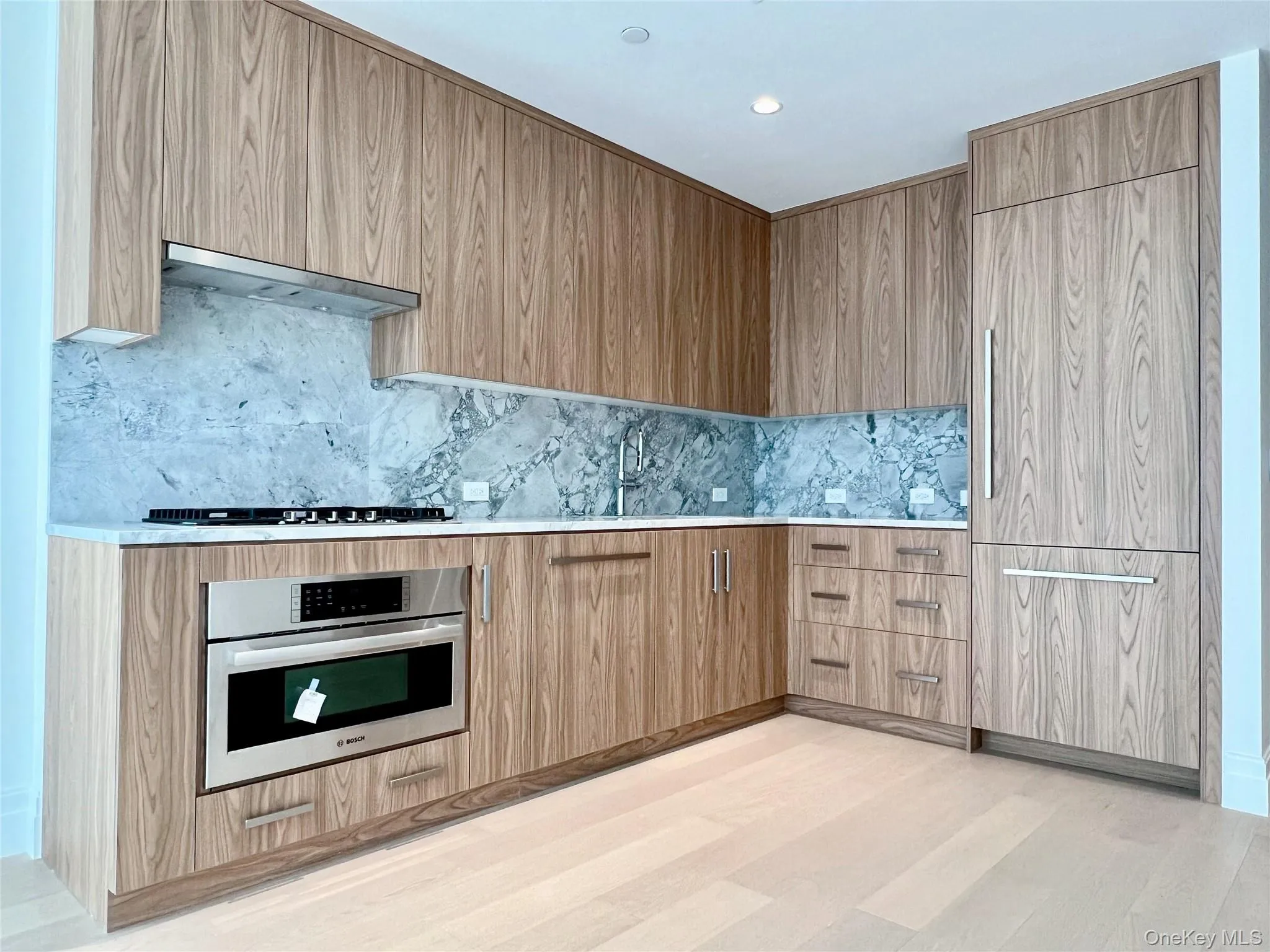 Kitchen with stainless steel oven, modern cabinets, backsplash, under cabinet range hood, and recessed lighting Kitchen with stainless steel oven, modern cabinets, backsplash, under cabinet range hood, and recessed lighting