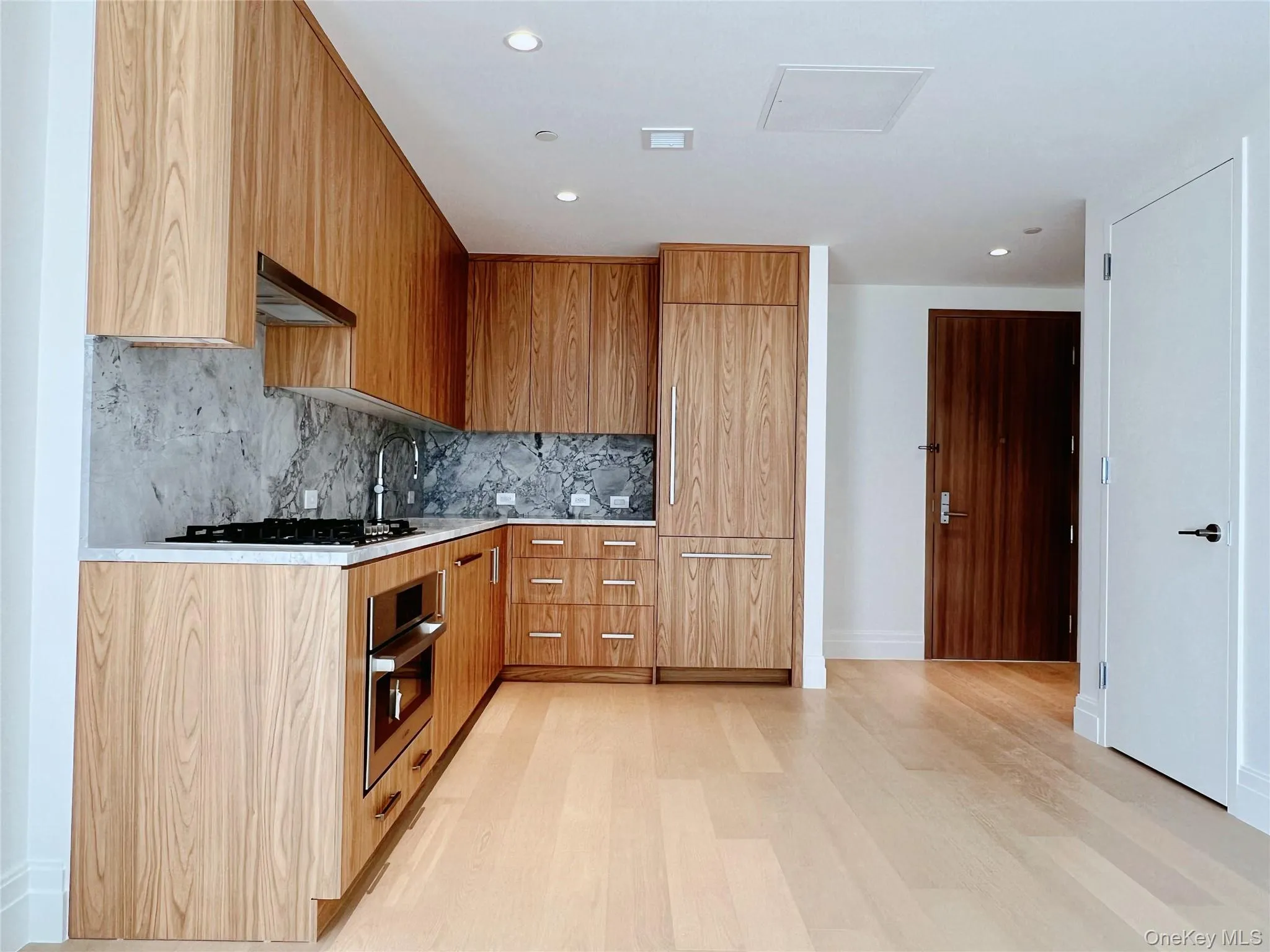 Kitchen with modern cabinets, appliances with stainless steel finishes, light stone countertops, recessed lighting, and ventilation hood Kitchen with modern cabinets, appliances with stainless steel finishes, light stone countertops, recessed lighting, and ventilation hood