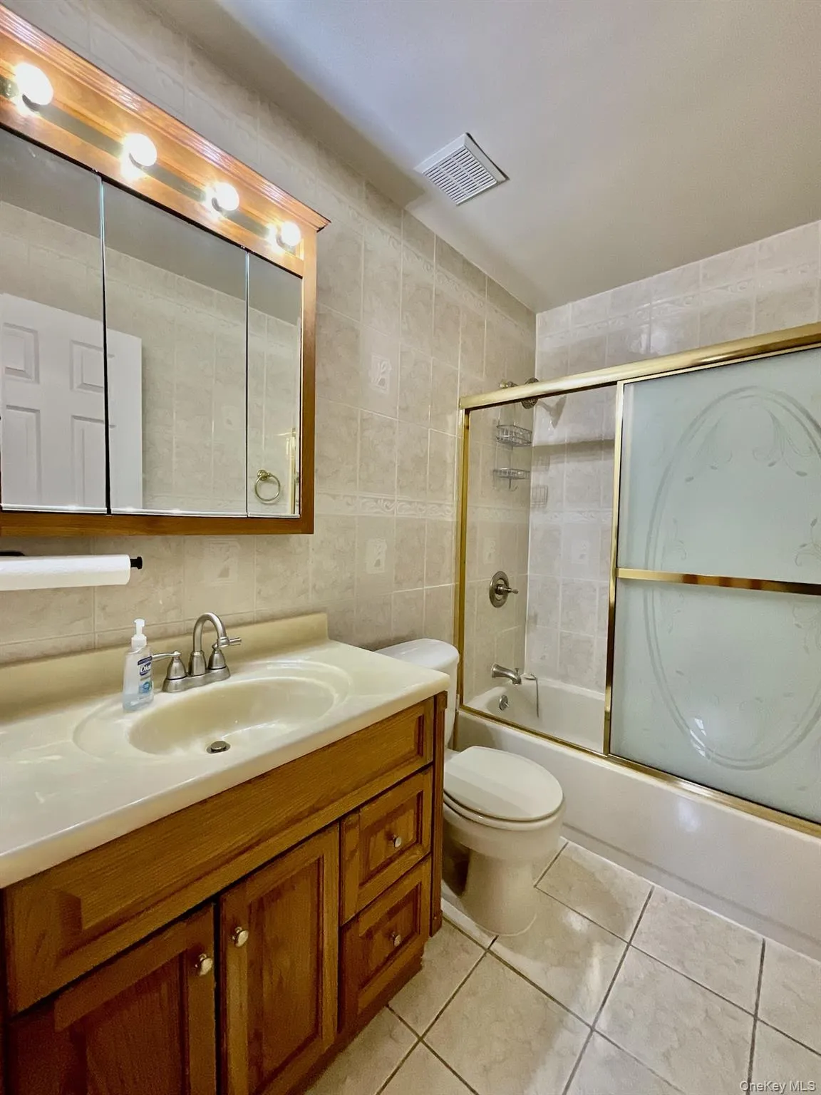 Full Bathroom with tile walls, shower / bath combination with glass door & vanity Full Bathroom with tile walls, shower / bath combination with glass door & vanity