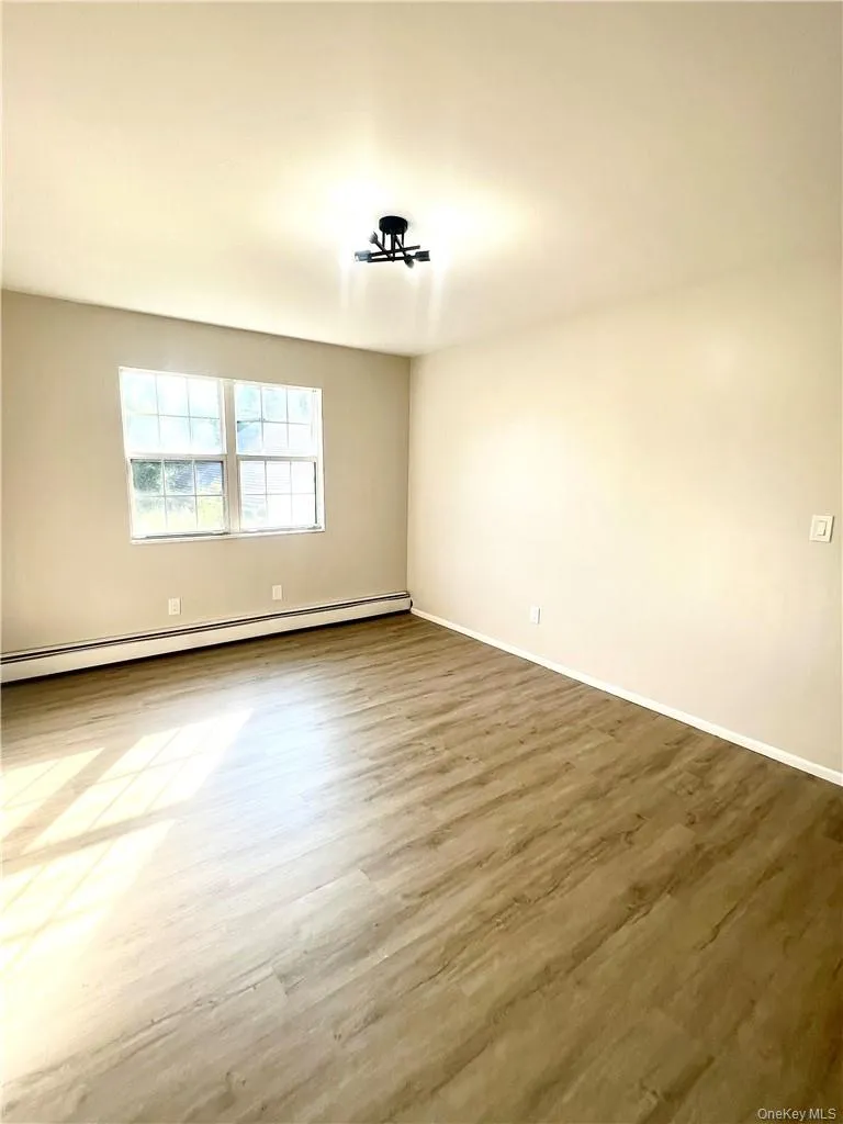 Spare room featuring light wood-type flooring and a baseboard heating unit Spare room featuring light wood-type flooring and a baseboard heating unit