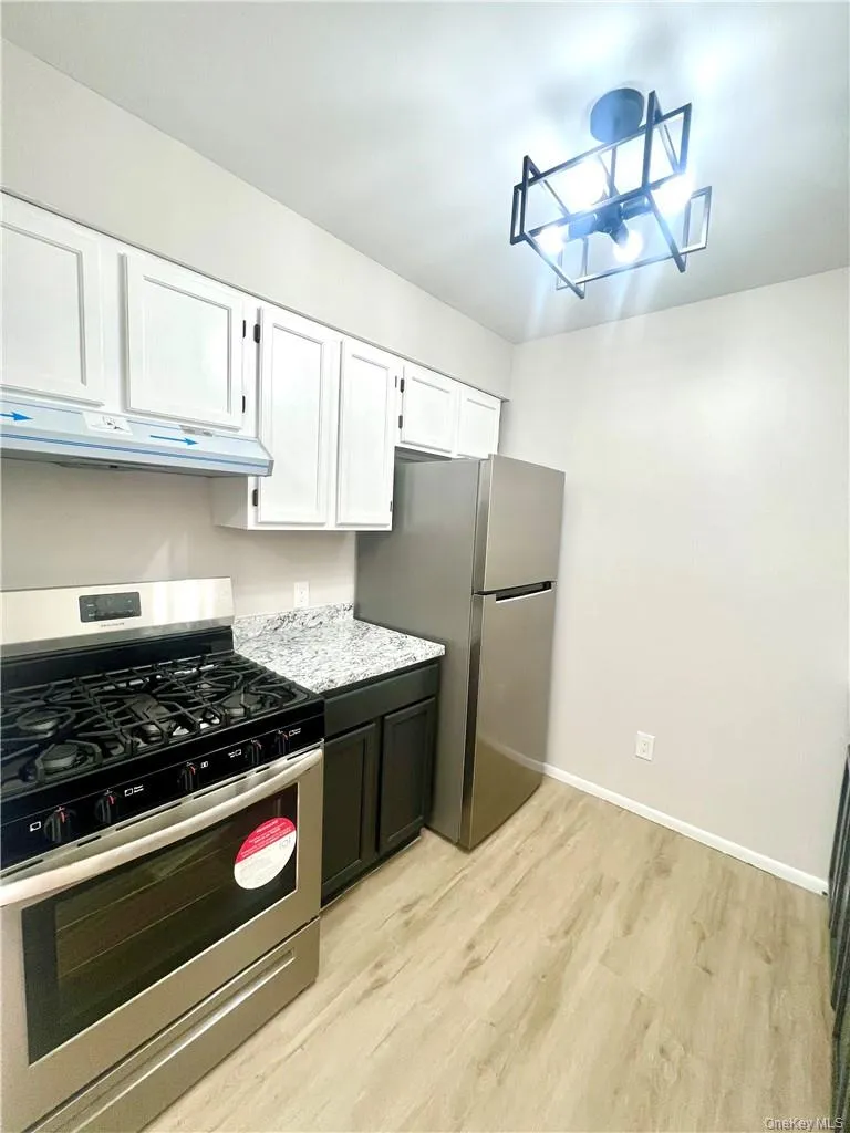 Kitchen featuring appliances with stainless steel finishes, white cabinetry, and light wood-type flooring Kitchen featuring appliances with stainless steel finishes, white cabinetry, and light wood-type flooring