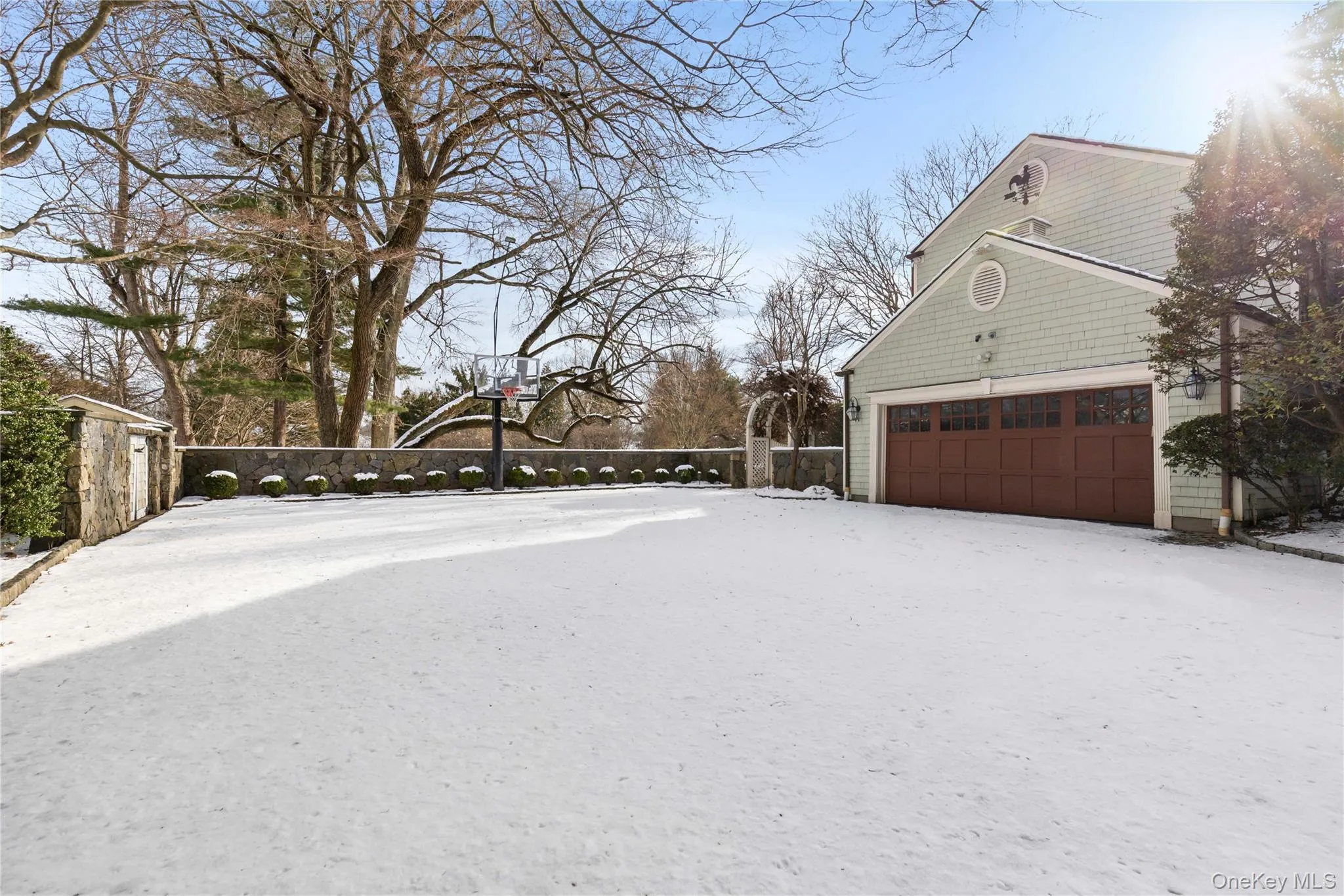 Snow covered vast driveway with garage and in-ground basketball hoop for play Snow covered vast driveway with garage and in-ground basketball hoop for play