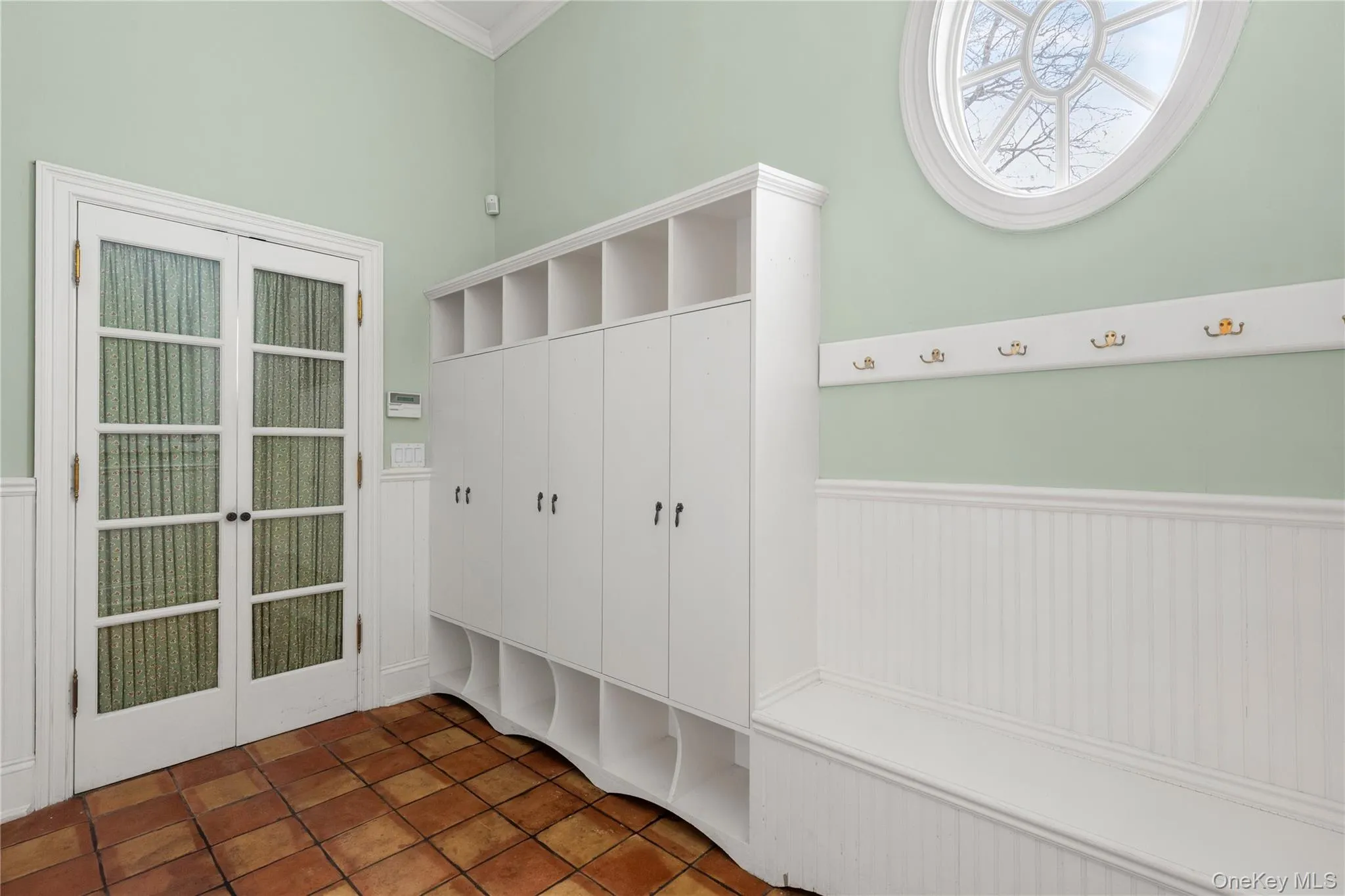 Sophisticated mudroom showcases wainscoting, custom millwork with organized built-in storage and seating plus large walk-in pantry in rear Sophisticated mudroom showcases wainscoting, custom millwork with organized built-in storage and seating plus large walk-in pantry in rear