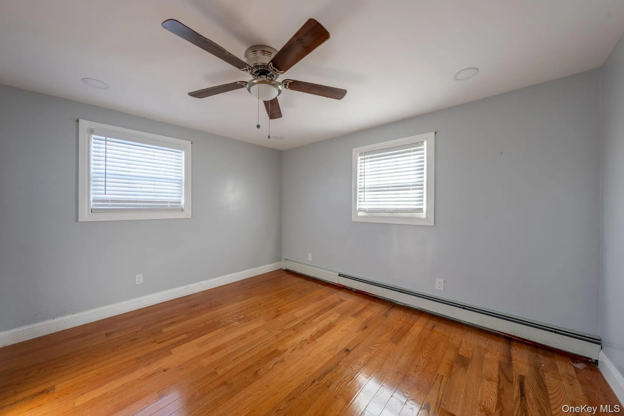 Spare room with a baseboard radiator, light wood finished floors, and ceiling fan Spare room with a baseboard radiator, light wood finished floors, and ceiling fan