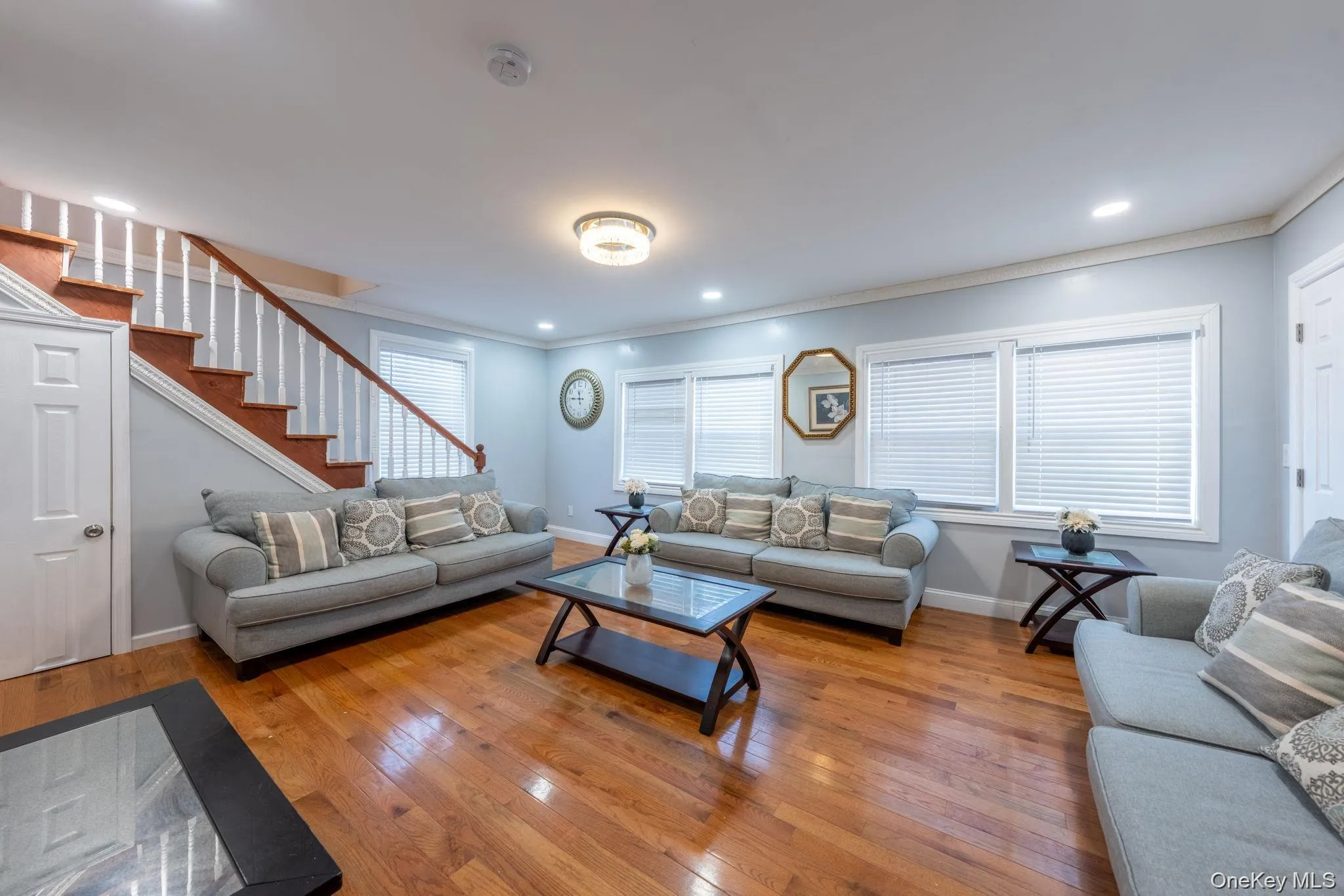 Living area featuring wood-type flooring, crown molding, stairs, and recessed lighting Living area featuring wood-type flooring, crown molding, stairs, and recessed lighting