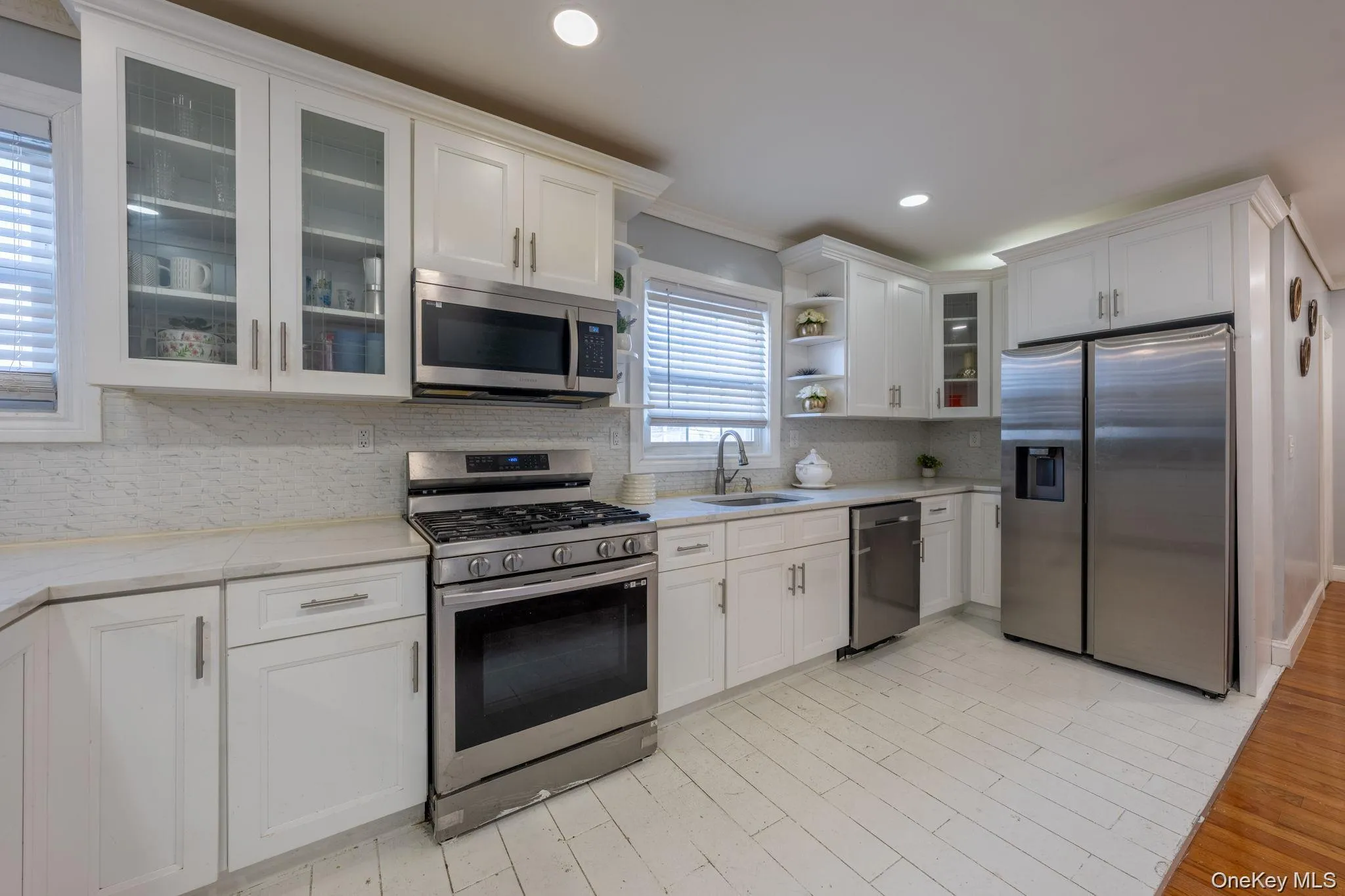 Kitchen featuring glass insert cabinets, open shelves, stainless steel appliances, white cabinetry, and recessed lighting Kitchen featuring glass insert cabinets, open shelves, stainless steel appliances, white cabinetry, and recessed lighting