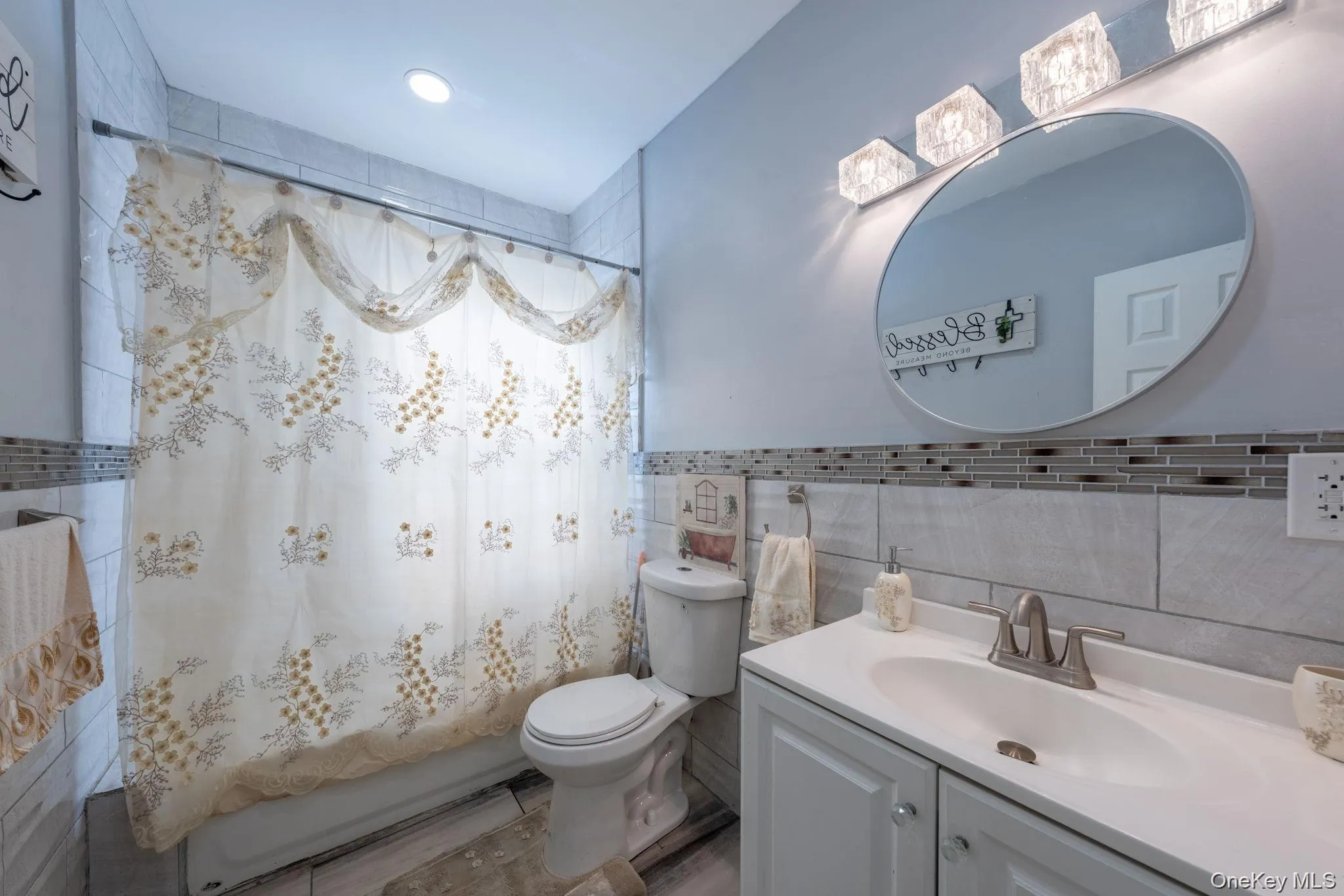 Bathroom with vanity, shower / bath combo with shower curtain, and tile walls Bathroom with vanity, shower / bath combo with shower curtain, and tile walls
