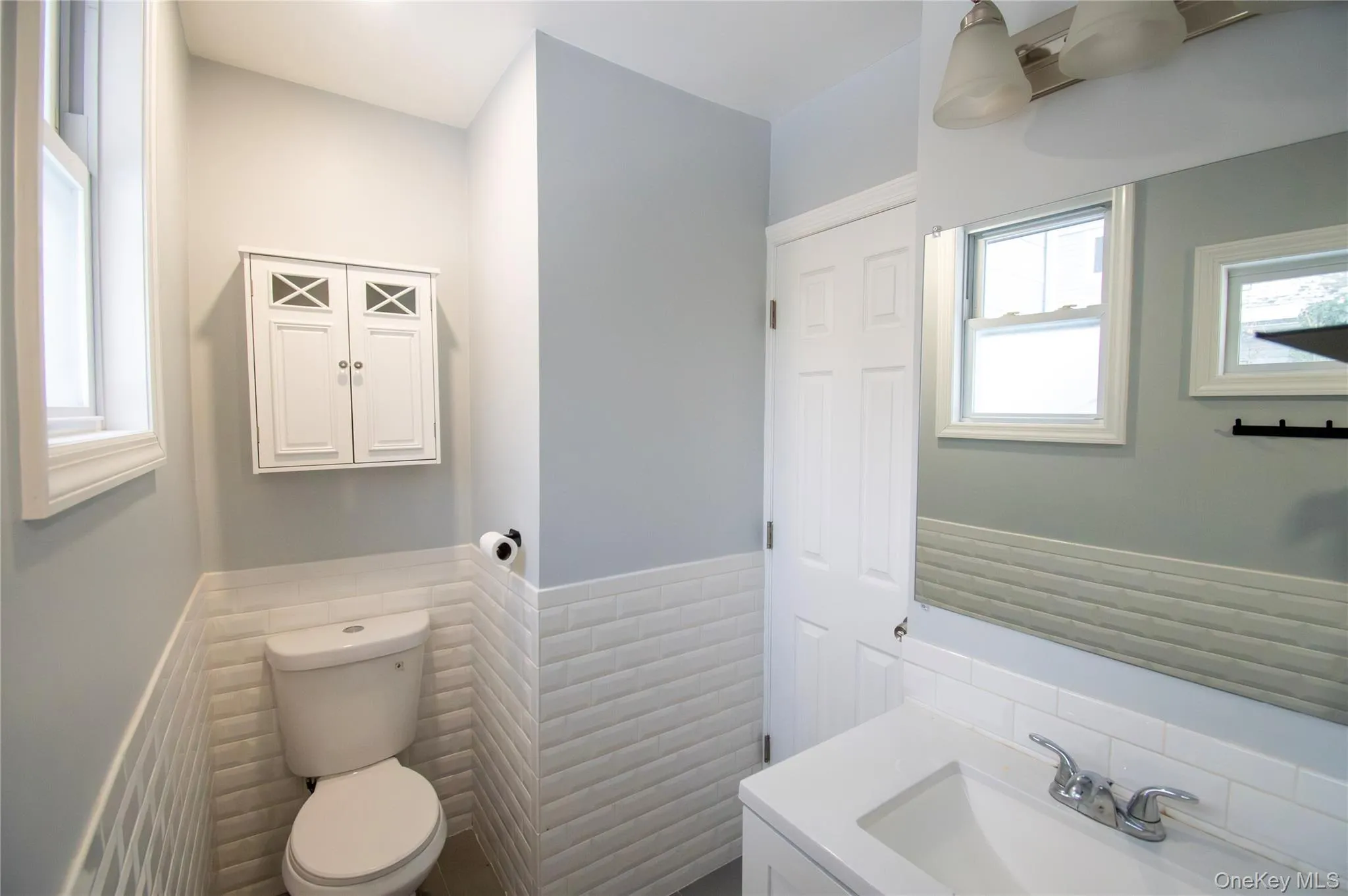 Bathroom with vanity, a wainscoted wall, and tile walls Bathroom with vanity, a wainscoted wall, and tile walls
