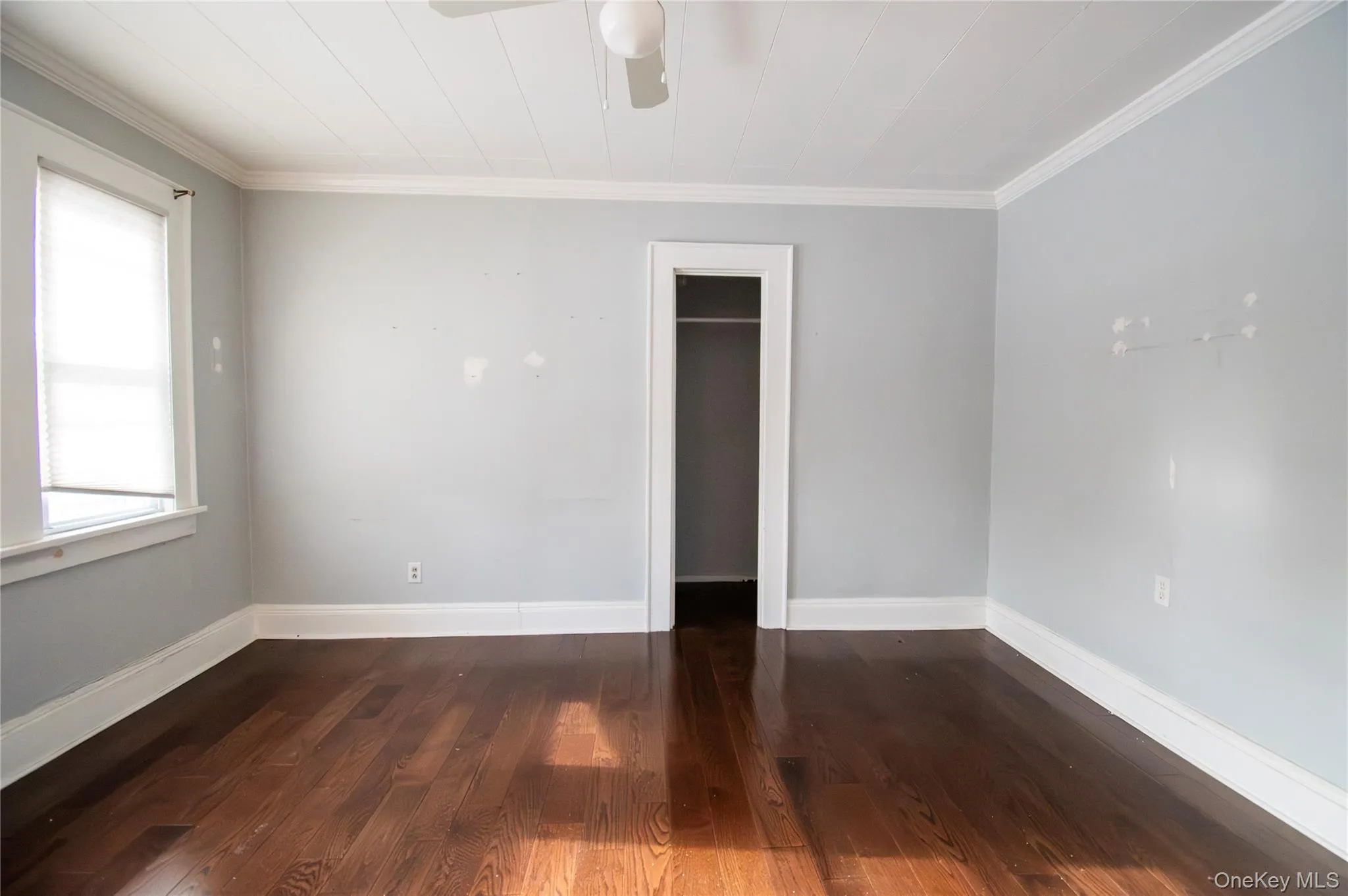 Unfurnished room with dark wood-style flooring, ornamental molding, and ceiling fan Unfurnished room with dark wood-style flooring, ornamental molding, and ceiling fan