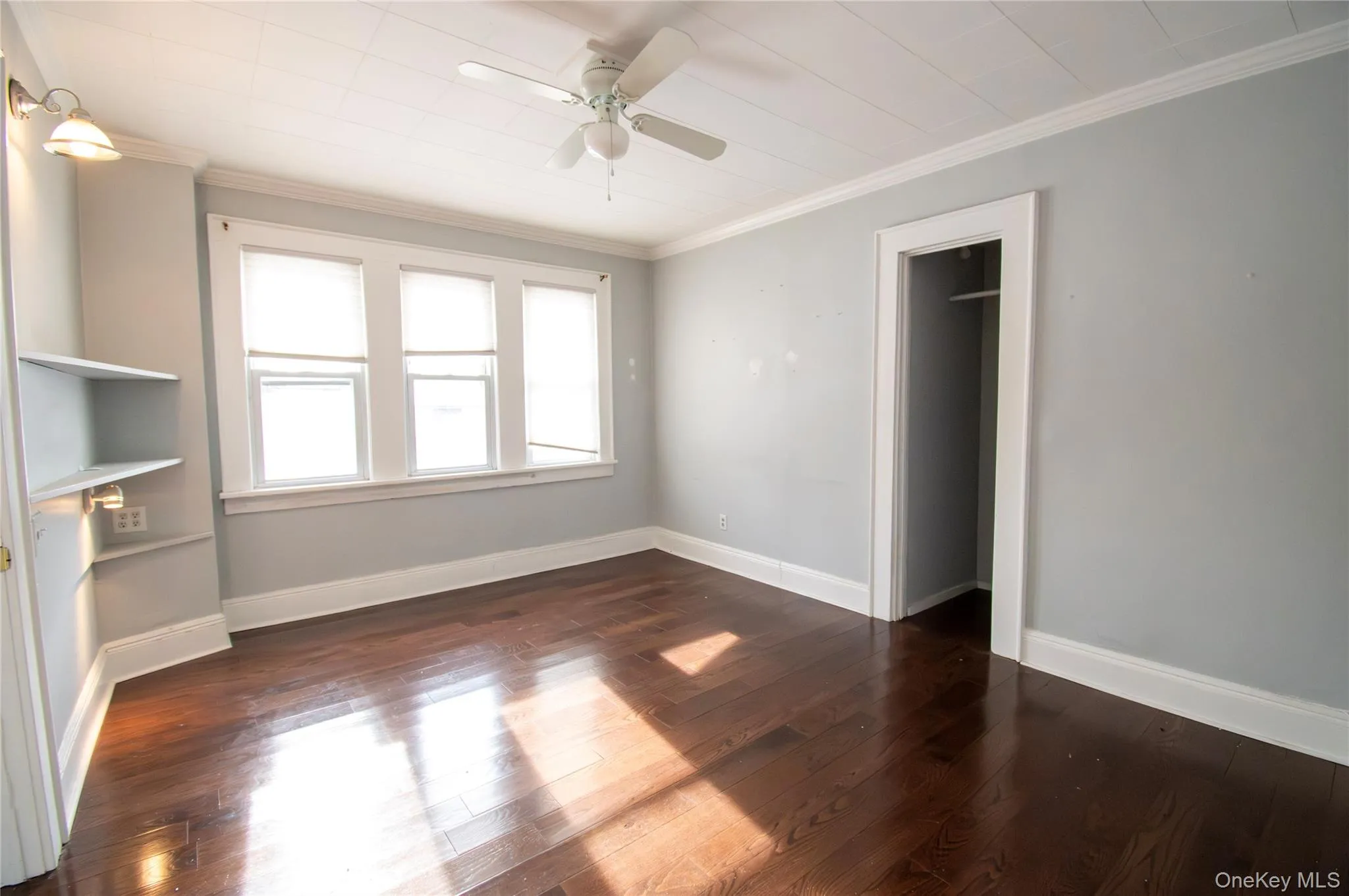 Unfurnished living room with ceiling fan, crown molding, and dark wood-style floors Unfurnished living room with ceiling fan, crown molding, and dark wood-style floors