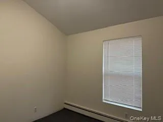 Empty room featuring a baseboard heating unit and dark carpet Empty room featuring a baseboard heating unit and dark carpet