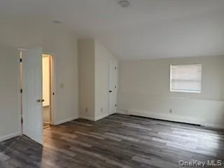 Unfurnished room featuring lofted ceiling and dark wood-style floors Unfurnished room featuring lofted ceiling and dark wood-style floors