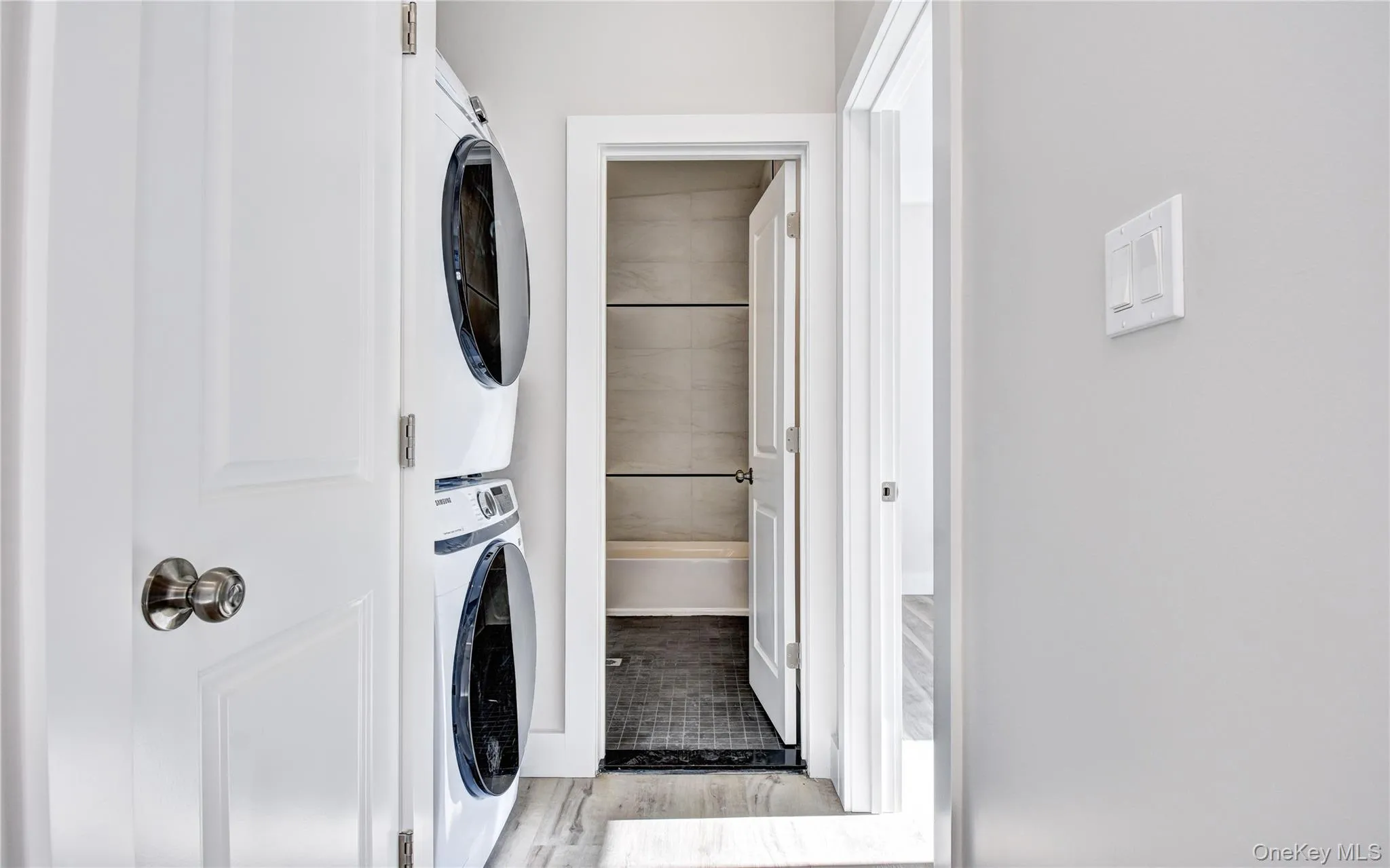 Laundry area with stacked washer / dryer and light wood-style flooring Laundry area with stacked washer / dryer and light wood-style flooring