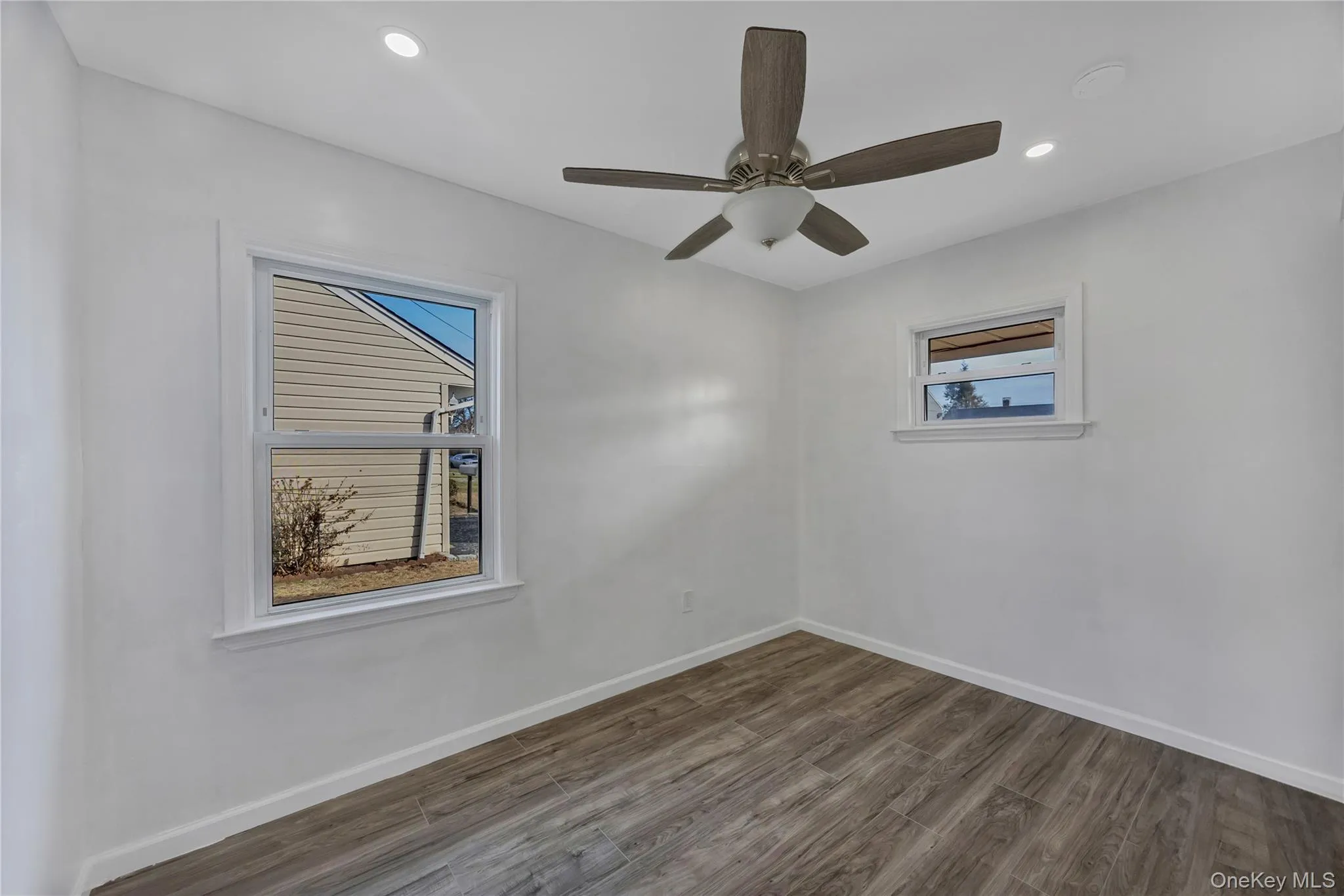 Empty room with dark wood finished floors, recessed lighting, and a ceiling fan Empty room with dark wood finished floors, recessed lighting, and a ceiling fan