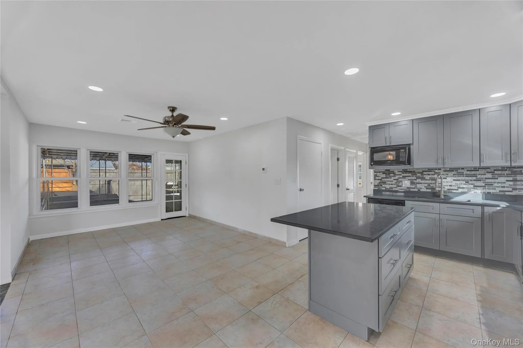 Kitchen with gray cabinets, a kitchen island, ceiling fan, recessed lighting, and dark stone countertops Kitchen with gray cabinets, a kitchen island, ceiling fan, recessed lighting, and dark stone countertops