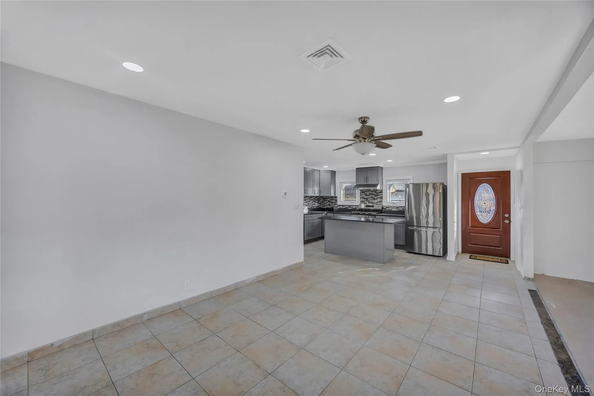 Kitchen with dark countertops, recessed lighting, freestanding refrigerator, gray cabinetry, and a center island Kitchen with dark countertops, recessed lighting, freestanding refrigerator, gray cabinetry, and a center island