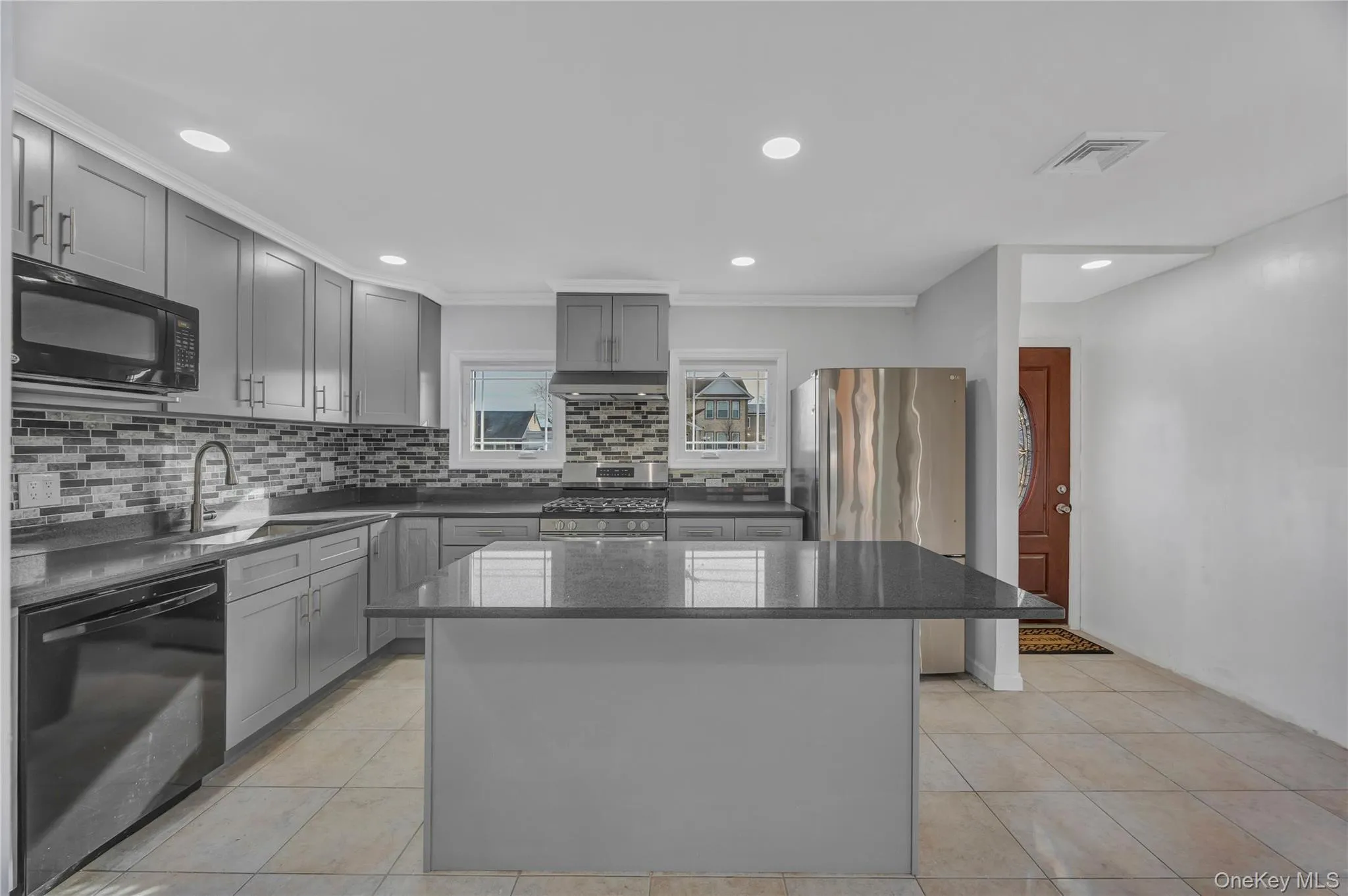 Kitchen featuring a kitchen island, gray cabinets, black appliances, dark stone counters, and recessed lighting Kitchen featuring a kitchen island, gray cabinets, black appliances, dark stone counters, and recessed lighting