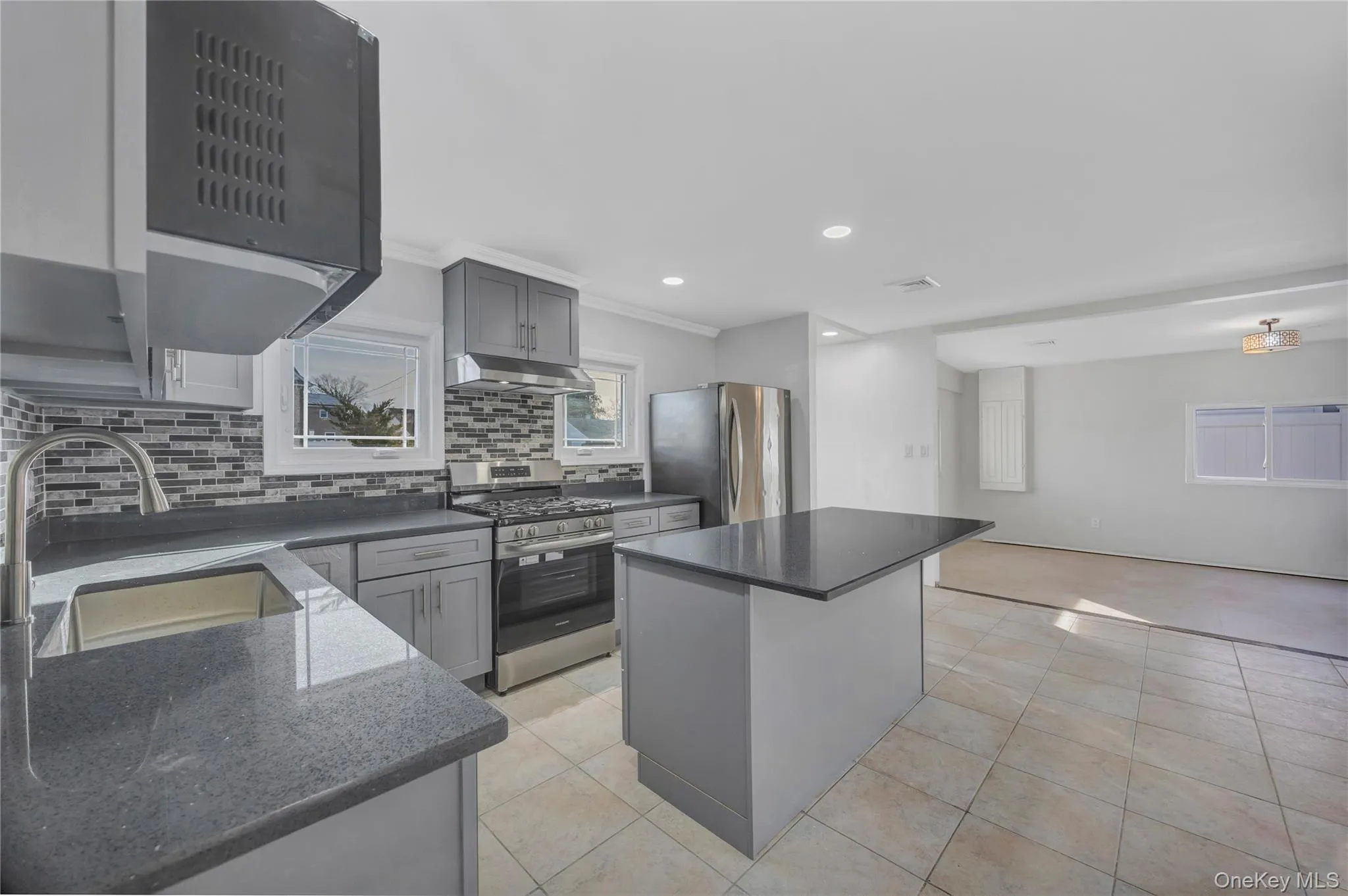 Kitchen featuring gray cabinets, a kitchen island, stainless steel appliances, recessed lighting, and dark stone countertops Kitchen featuring gray cabinets, a kitchen island, stainless steel appliances, recessed lighting, and dark stone countertops