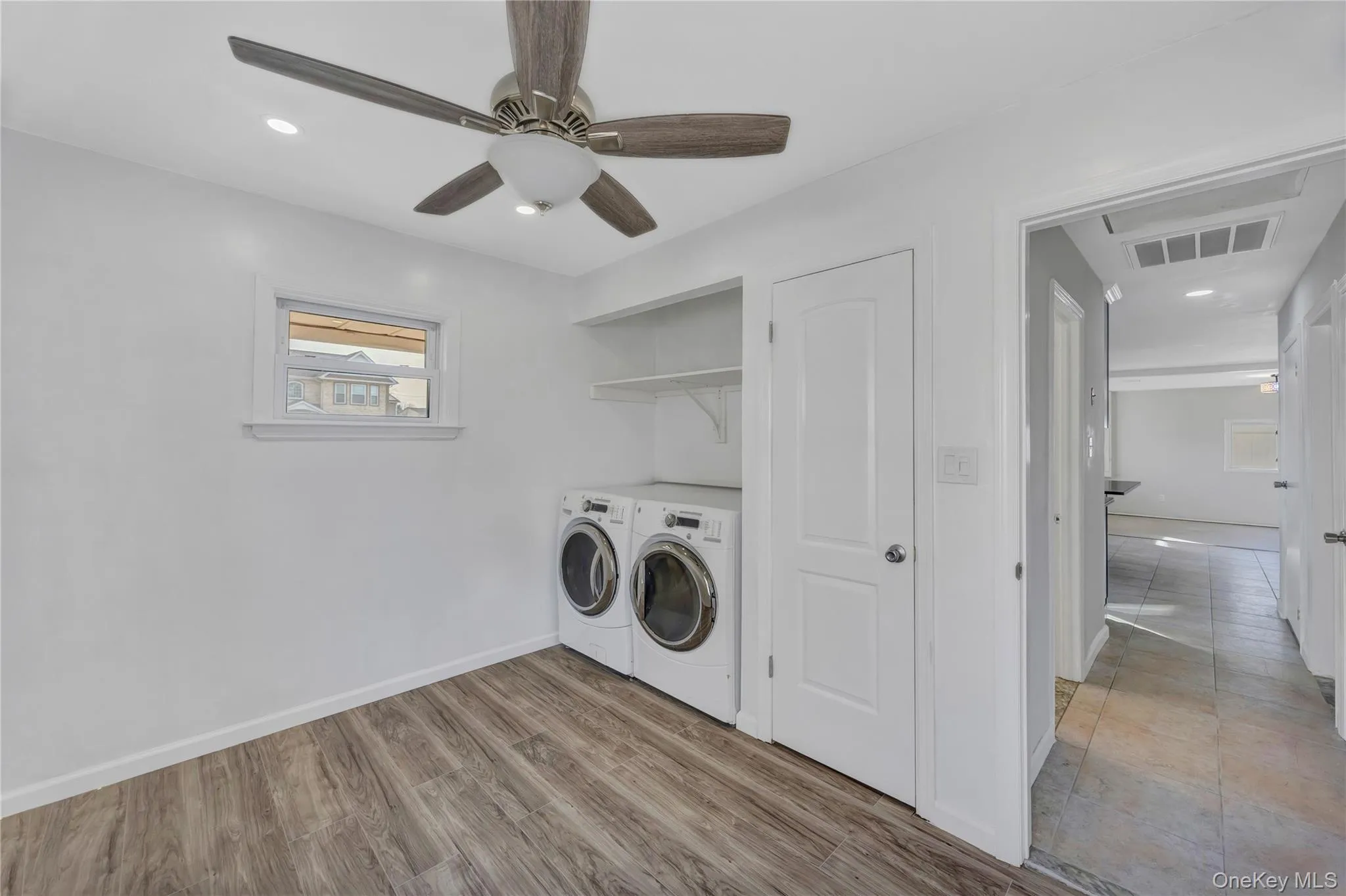 Washroom with a ceiling fan, washer and clothes dryer, wood finished floors, and recessed lighting Washroom with a ceiling fan, washer and clothes dryer, wood finished floors, and recessed lighting