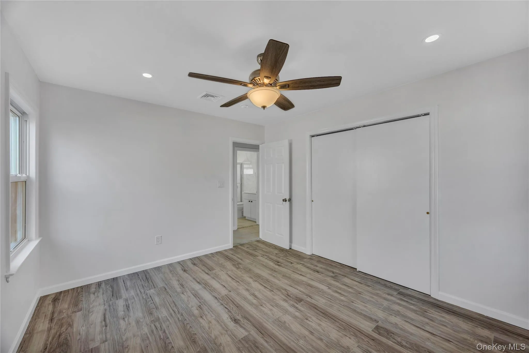 Unfurnished bedroom with recessed lighting, light wood-type flooring, a closet, a ceiling fan, and multiple windows Unfurnished bedroom with recessed lighting, light wood-type flooring, a closet, a ceiling fan, and multiple windows