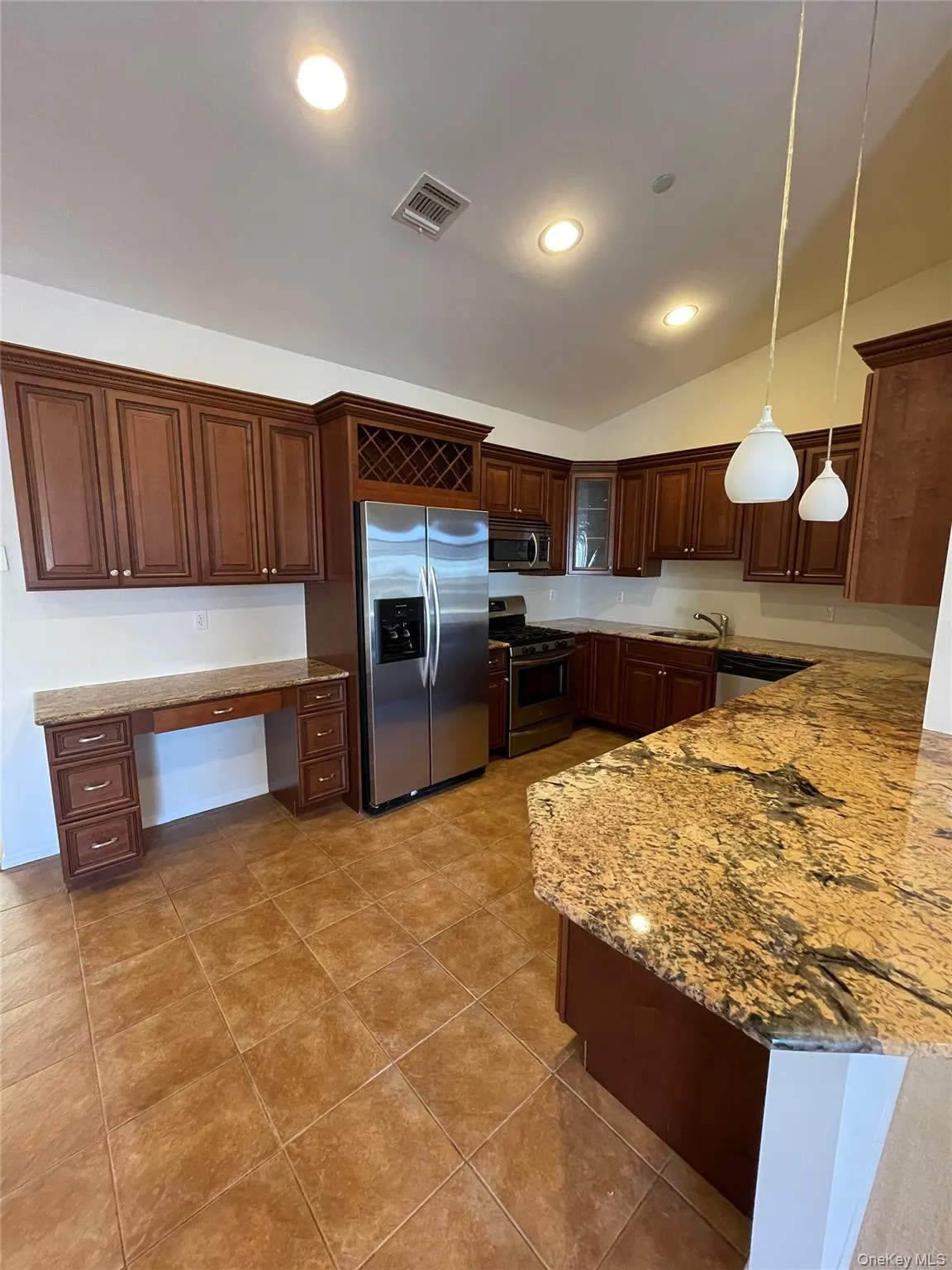 Kitchen with light stone countertops, appliances with stainless steel finishes, pendant lighting, lofted ceiling, and recessed lighting Kitchen with light stone countertops, appliances with stainless steel finishes, pendant lighting, lofted ceiling, and recessed lighting