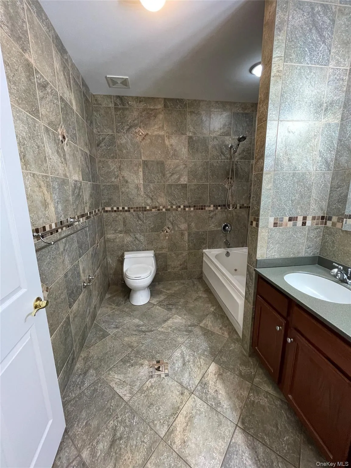 Full bathroom with tile walls, shower / bath combination, and vanity Full bathroom with tile walls, shower / bath combination, and vanity