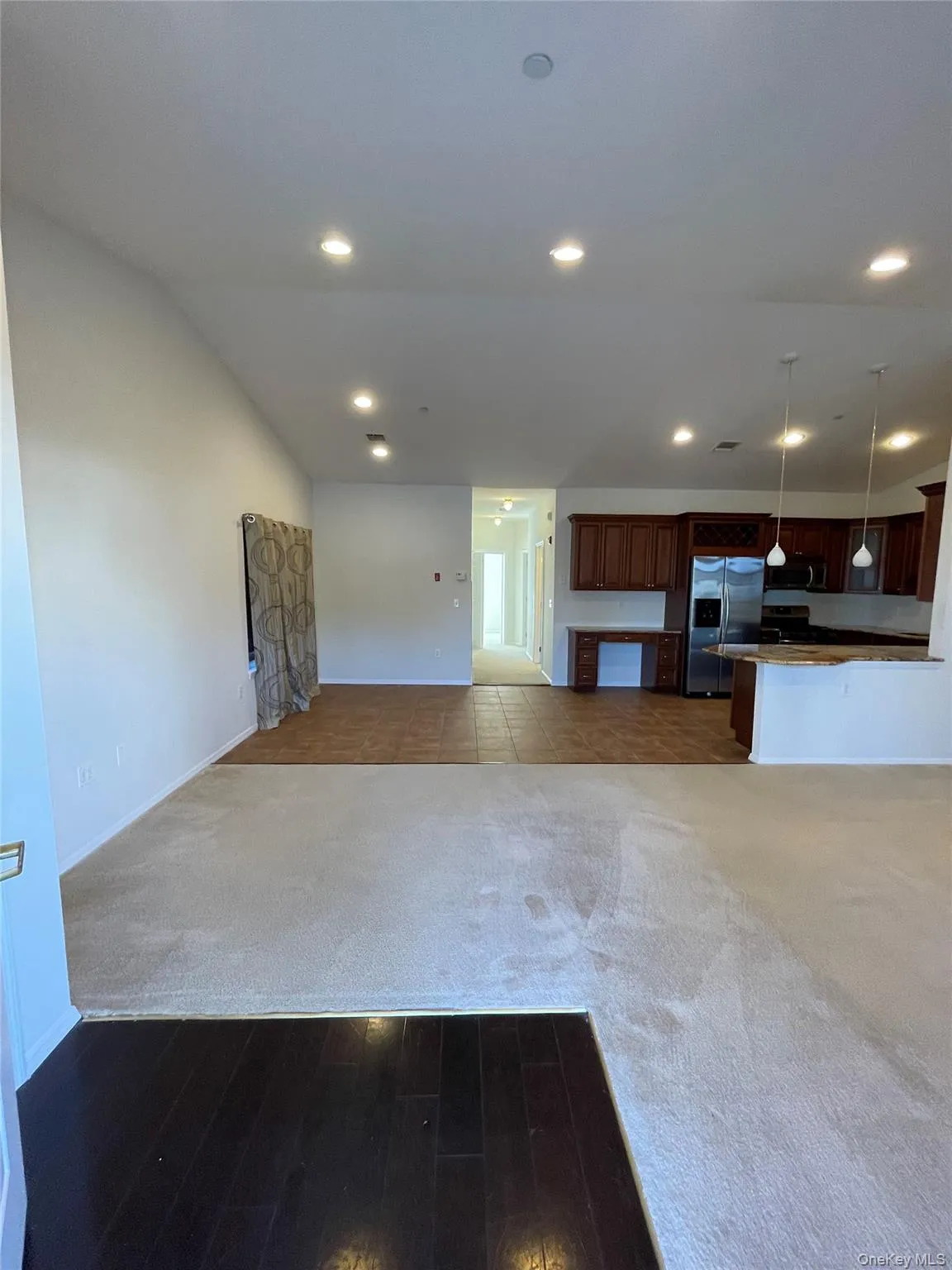 Kitchen featuring open floor plan, dark carpet, stainless steel refrigerator with ice dispenser, pendant lighting, and recessed lighting Kitchen featuring open floor plan, dark carpet, stainless steel refrigerator with ice dispenser, pendant lighting, and recessed lighting