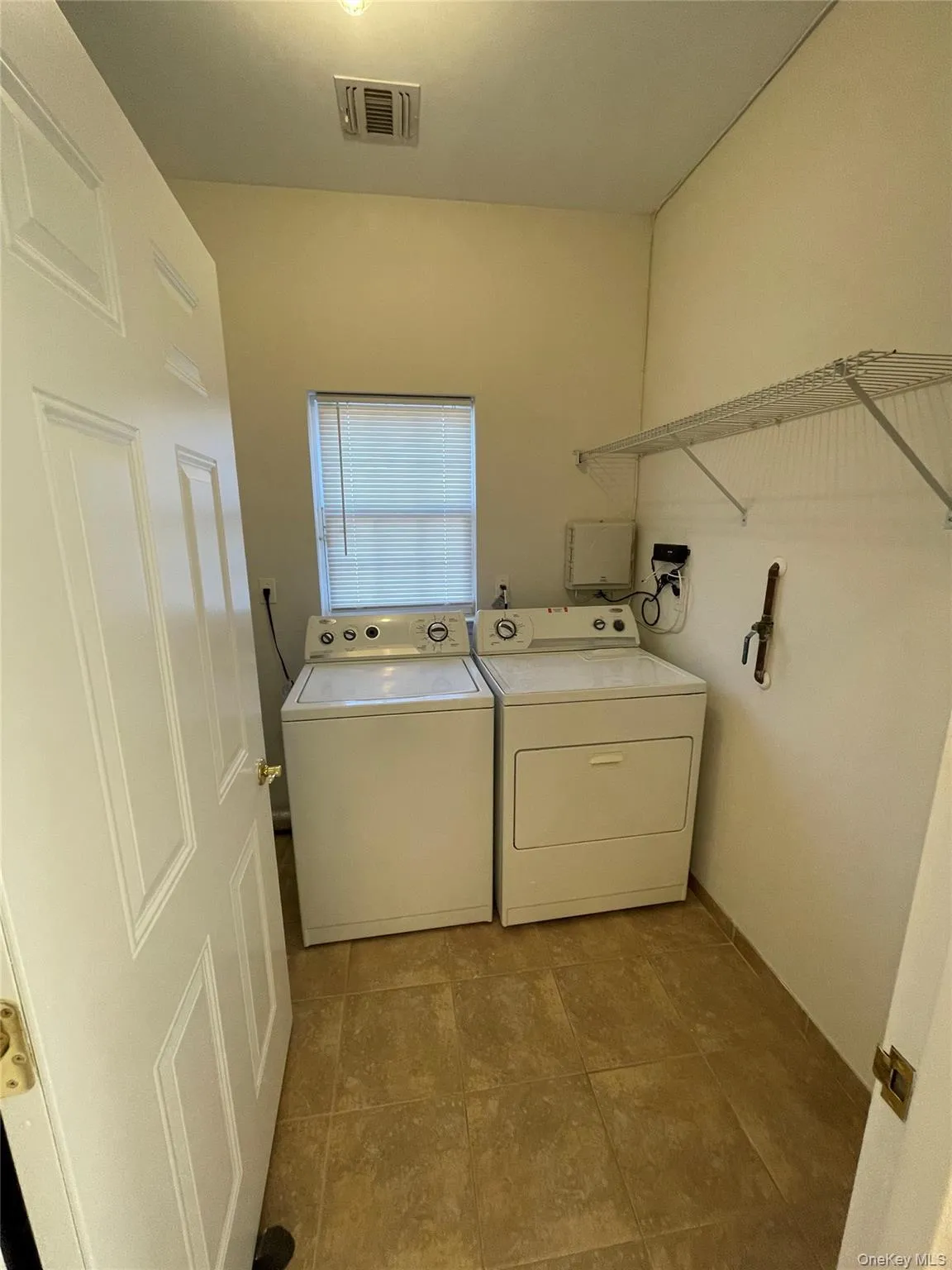 Washroom with washer and clothes dryer and light tile patterned floors Washroom with washer and clothes dryer and light tile patterned floors