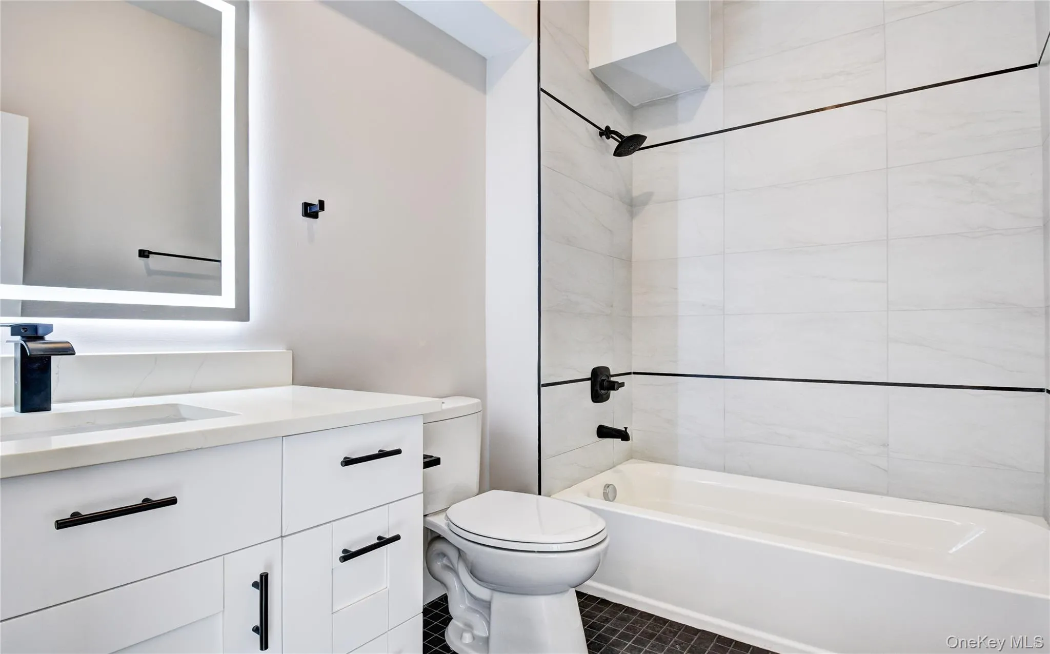 Full bathroom with vanity, bathing tub / shower combination, and dark tile patterned floors Full bathroom with vanity, bathing tub / shower combination, and dark tile patterned floors