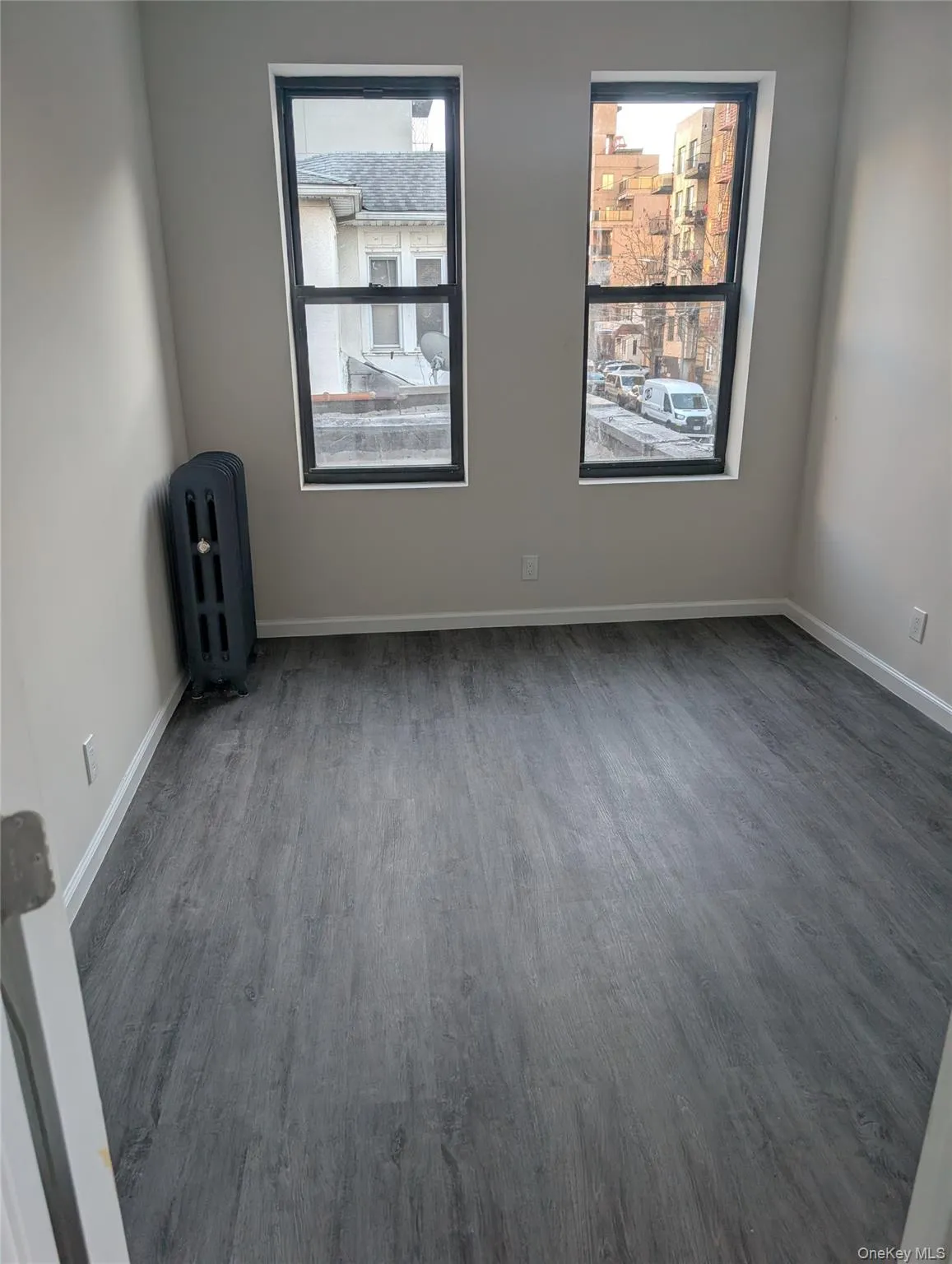 Spare room featuring radiator heating unit and wood finished floors Spare room featuring radiator heating unit and wood finished floors