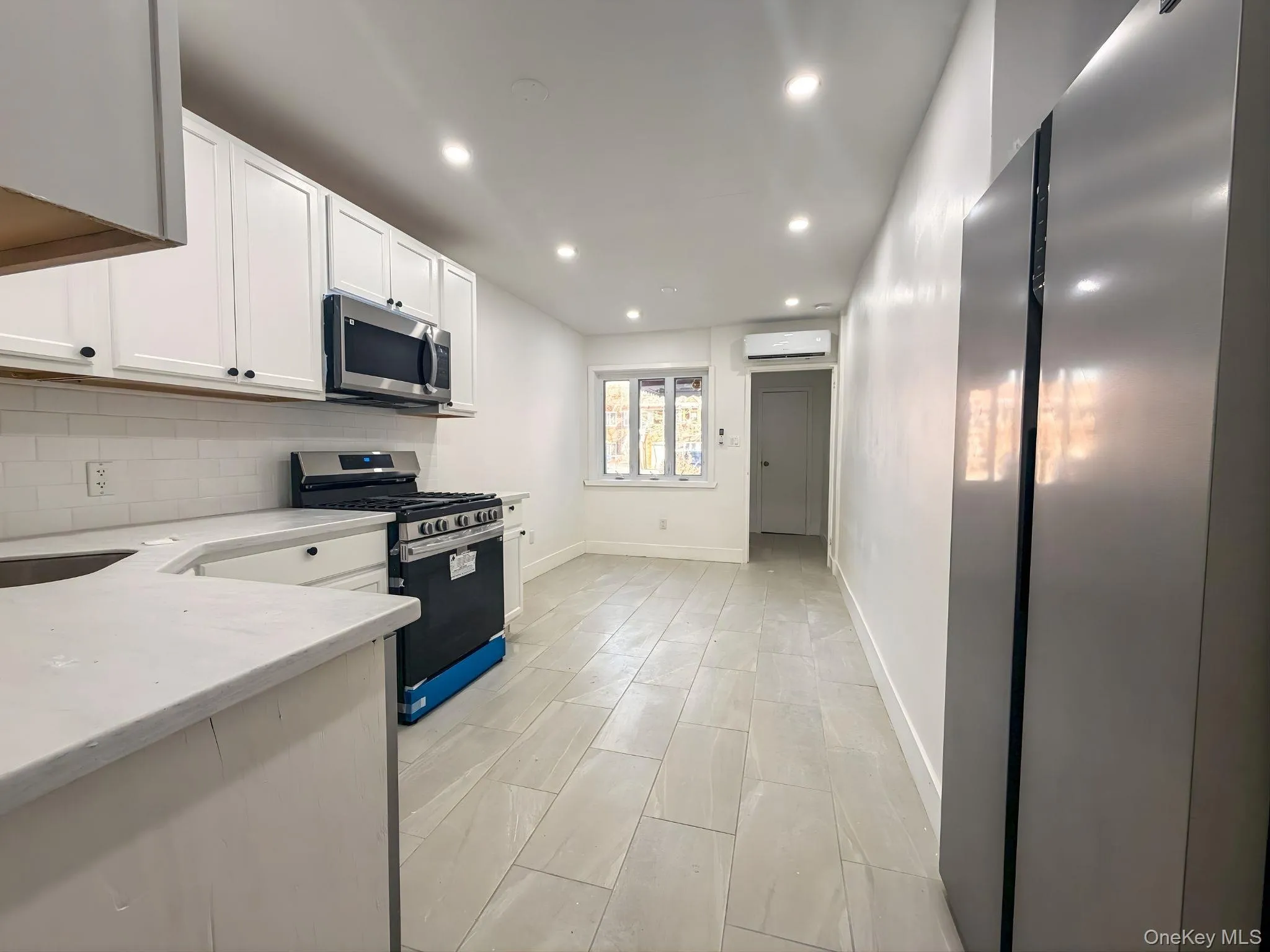 Kitchen featuring appliances with stainless steel finishes, white cabinets, recessed lighting, light stone countertops, and tasteful backsplash Kitchen featuring appliances with stainless steel finishes, white cabinets, recessed lighting, light stone countertops, and tasteful backsplash