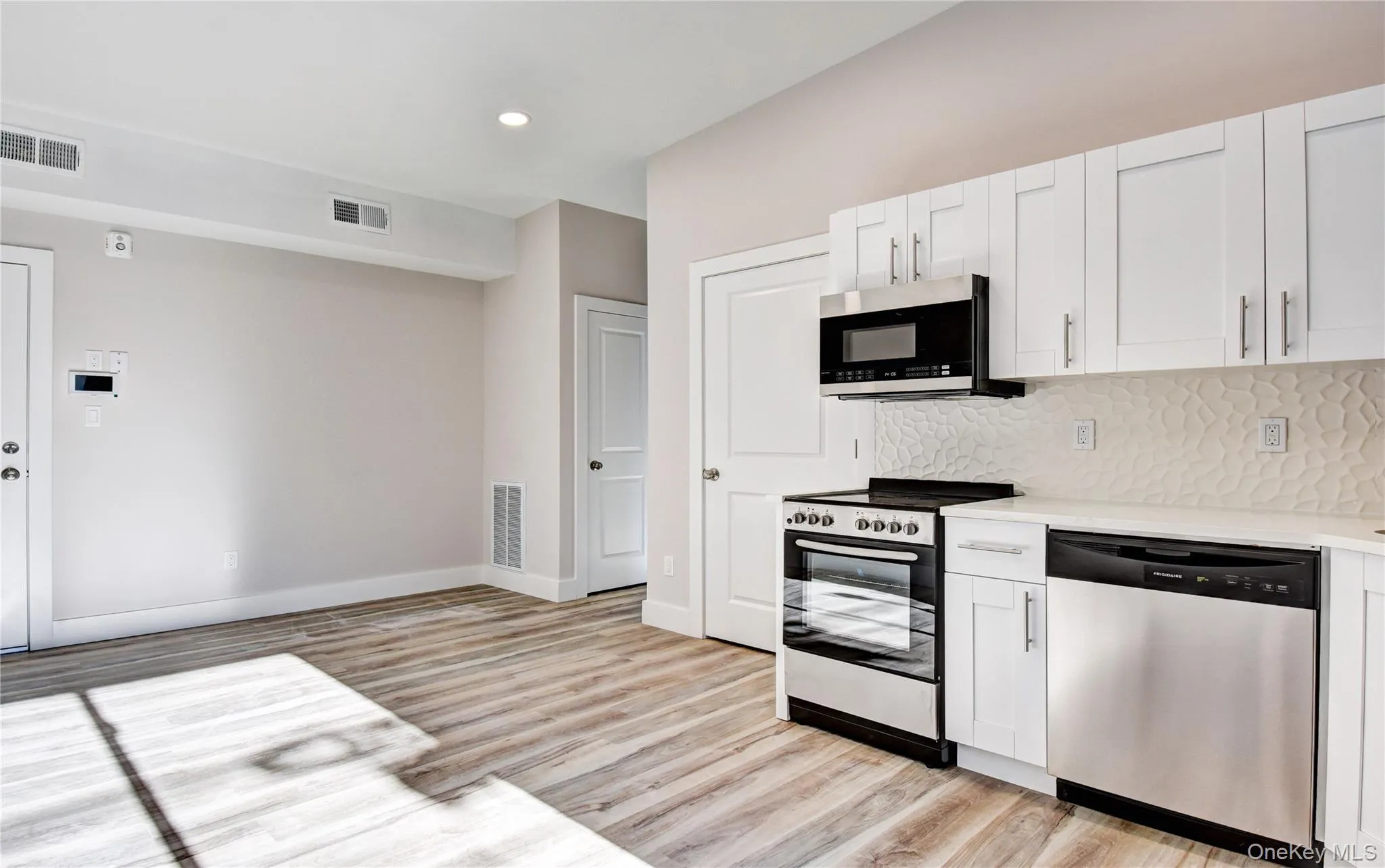 Kitchen featuring appliances with stainless steel finishes, white cabinetry, light wood finished floors, backsplash, and recessed lighting Kitchen featuring appliances with stainless steel finishes, white cabinetry, light wood finished floors, backsplash, and recessed lighting