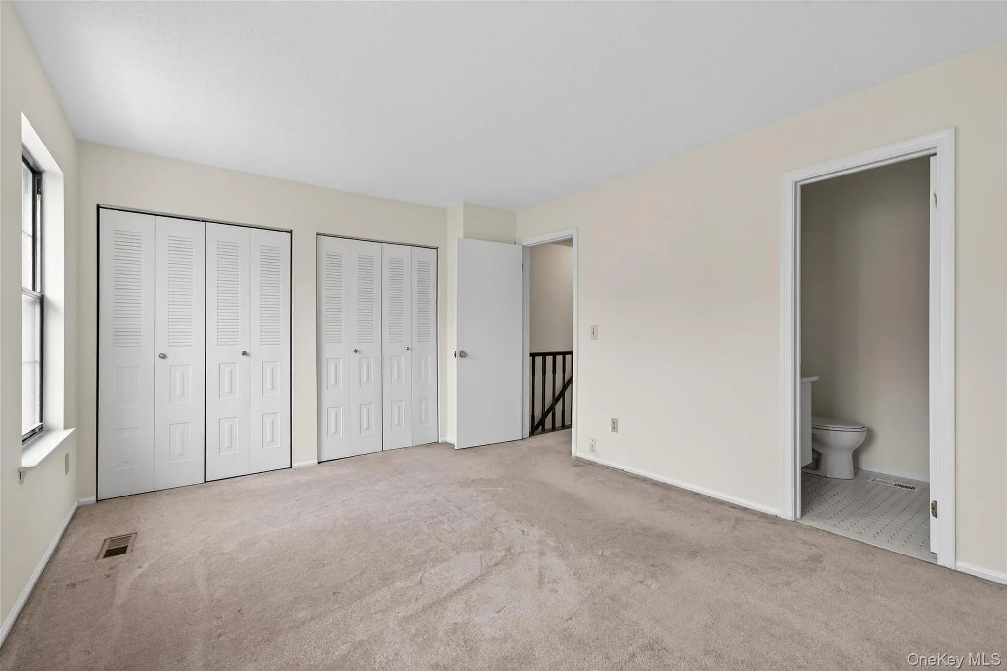 Unfurnished bedroom with two closets, carpet floors, and ensuite bath Unfurnished bedroom with two closets, carpet floors, and ensuite bath
