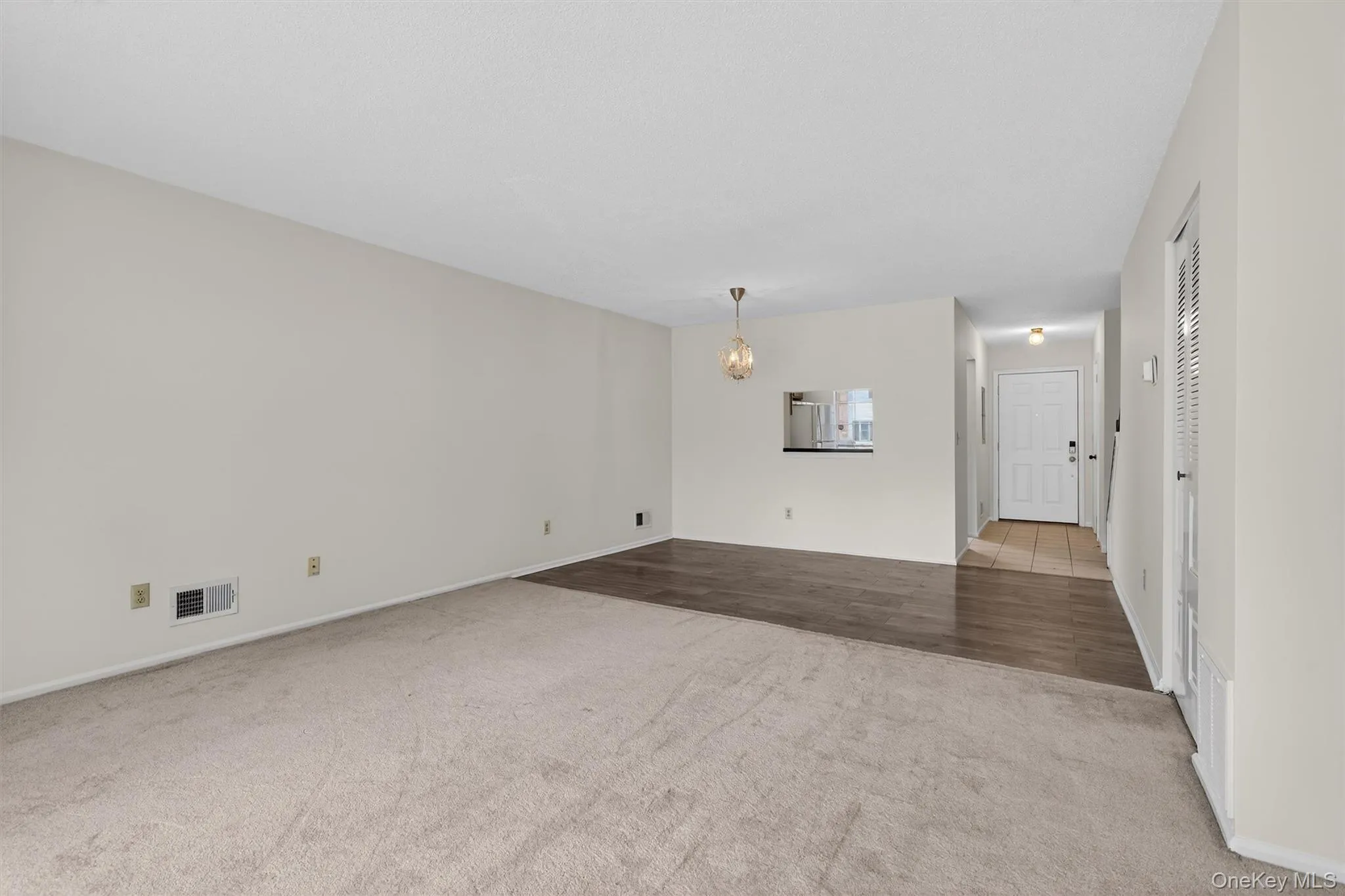 Unfurnished living room with a chandelier and light colored carpet Unfurnished living room with a chandelier and light colored carpet