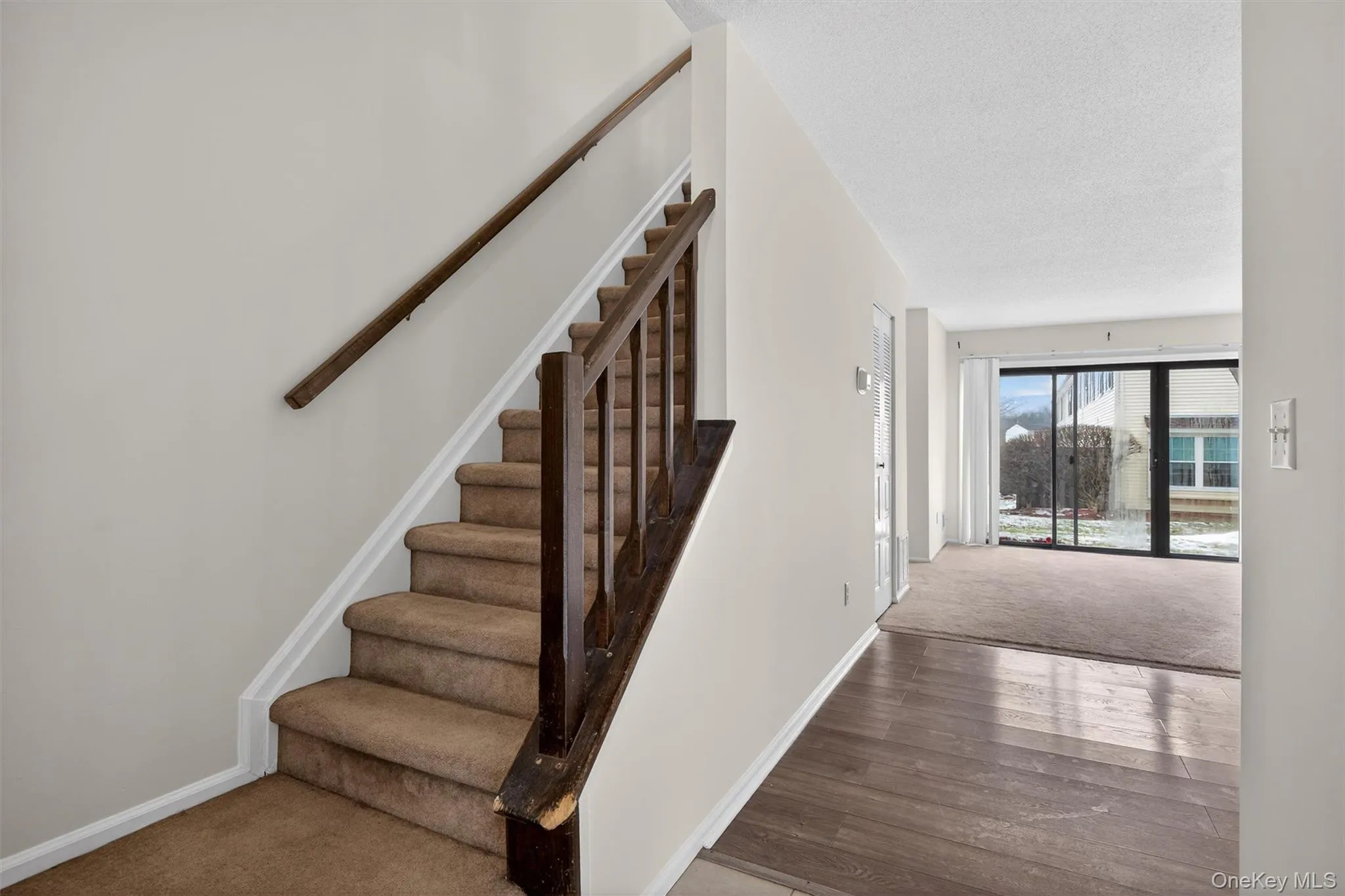 Stairway featuring carpet floors and a textured ceiling Stairway featuring carpet floors and a textured ceiling