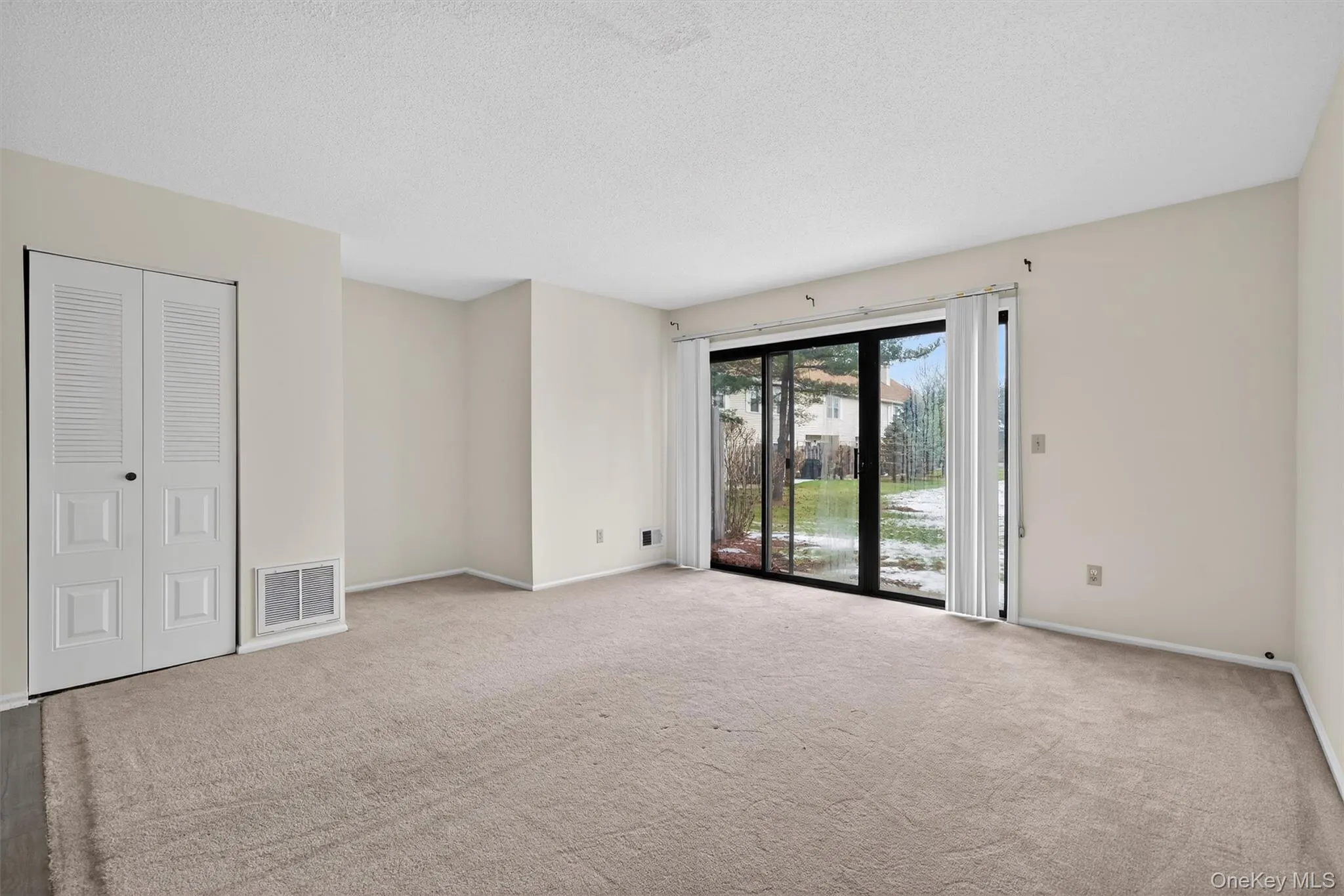 Carpeted empty room with a textured ceiling and baseboards Carpeted empty room with a textured ceiling and baseboards