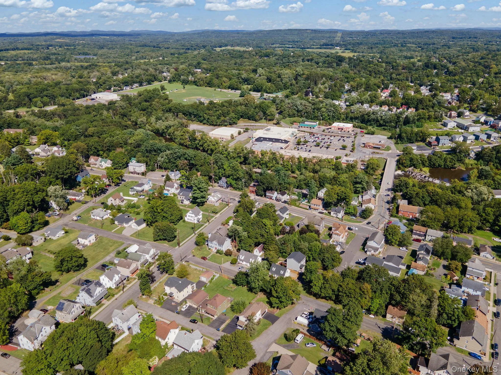 Aerial view of property and surrounding area with nearby suburban area and a tree filled landscape Aerial view of property and surrounding area with nearby suburban area and a tree filled landscape