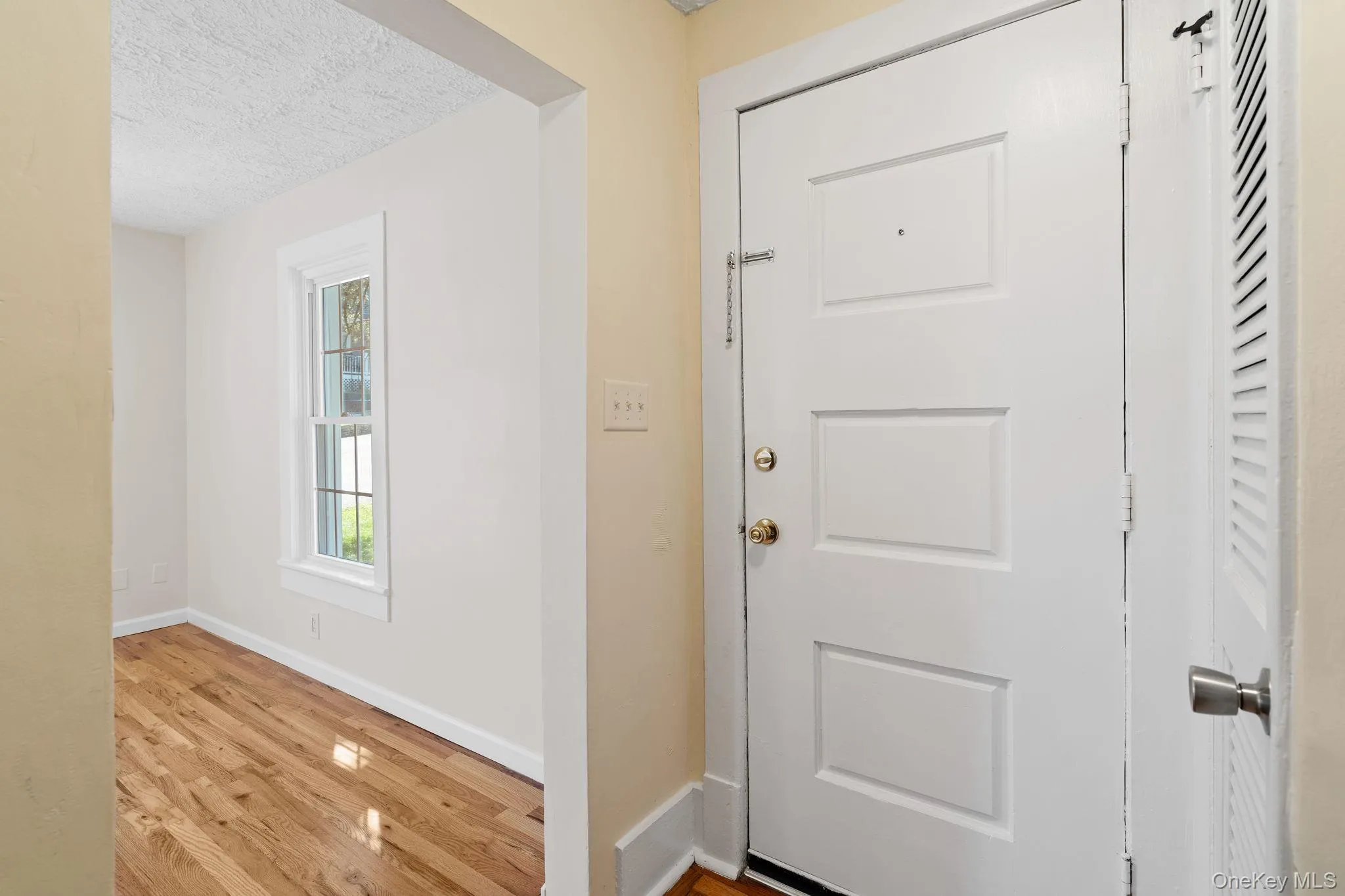 Foyer entrance featuring light wood-type flooring and a textured ceiling Foyer entrance featuring light wood-type flooring and a textured ceiling