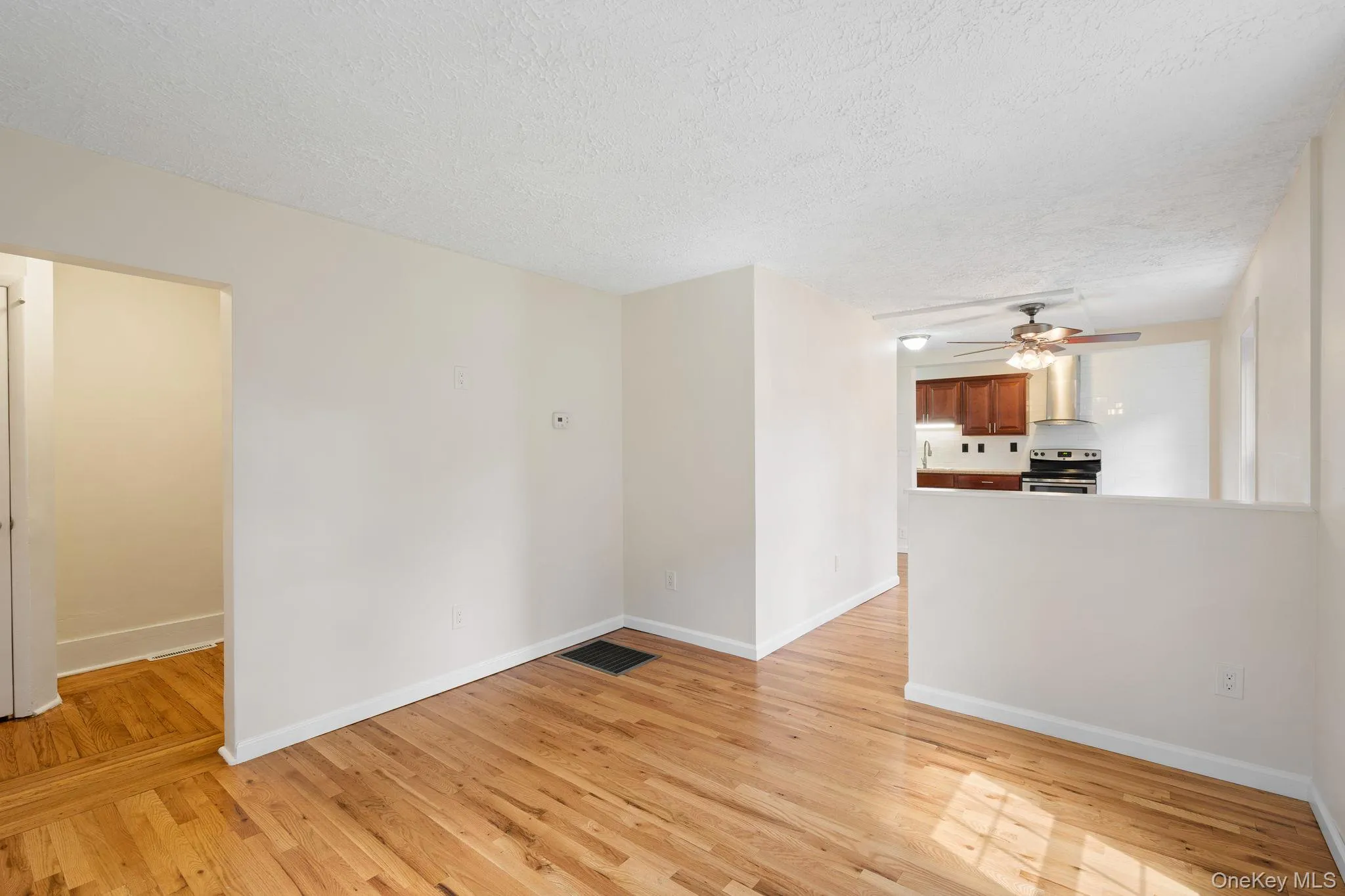Unfurnished room featuring light wood finished floors, a textured ceiling, and ceiling fan Unfurnished room featuring light wood finished floors, a textured ceiling, and ceiling fan