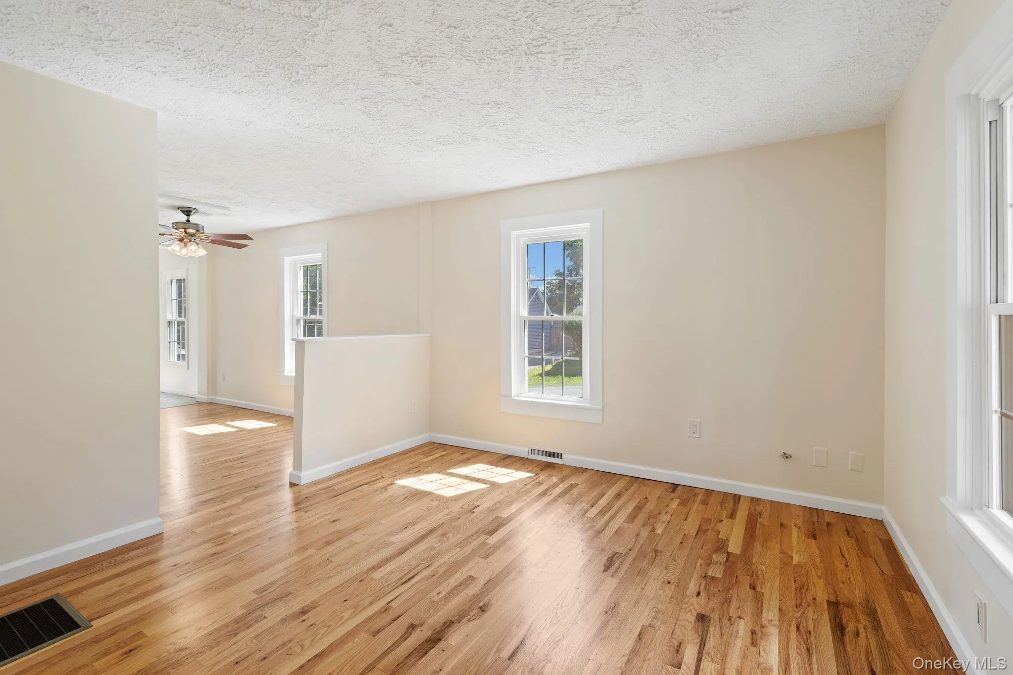Unfurnished room with light wood-style flooring, a textured ceiling, and ceiling fan Unfurnished room with light wood-style flooring, a textured ceiling, and ceiling fan