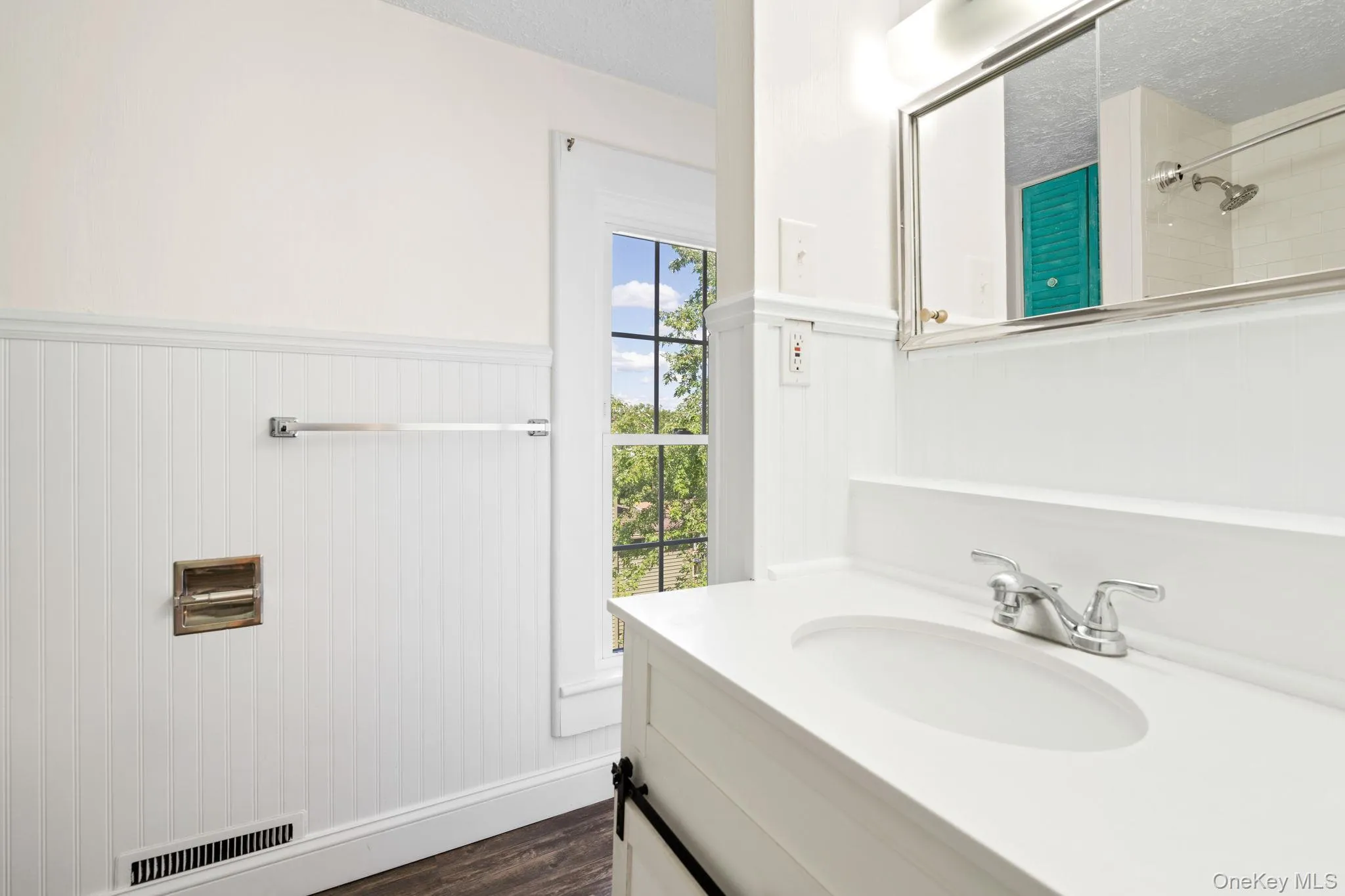 Bathroom featuring vanity, dark wood-style floors, a wainscoted wall, a shower, and a textured ceiling Bathroom featuring vanity, dark wood-style floors, a wainscoted wall, a shower, and a textured ceiling