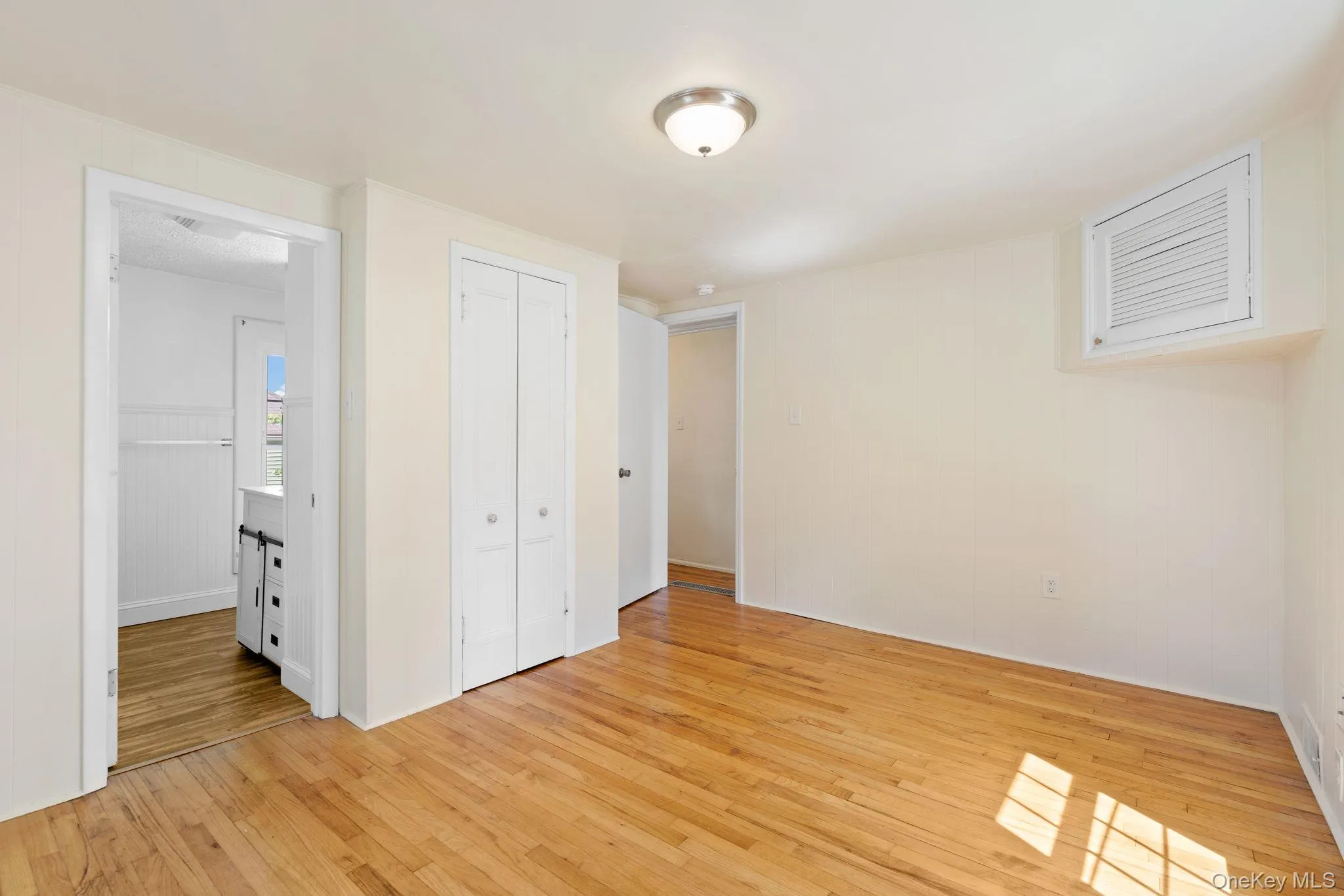 Unfurnished bedroom featuring light wood finished floors, a closet, and wooden walls Unfurnished bedroom featuring light wood finished floors, a closet, and wooden walls