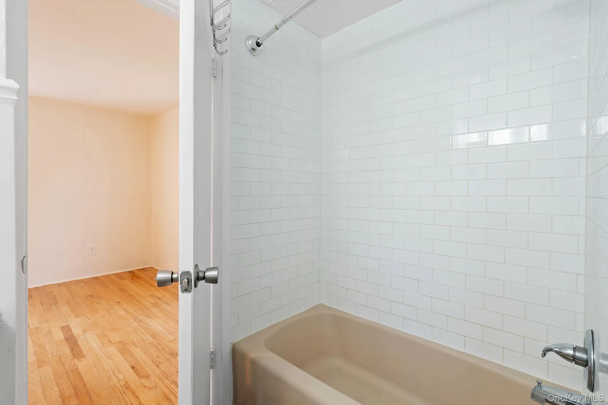 Bathroom featuring bathtub / shower combination and light wood finished floors Bathroom featuring bathtub / shower combination and light wood finished floors