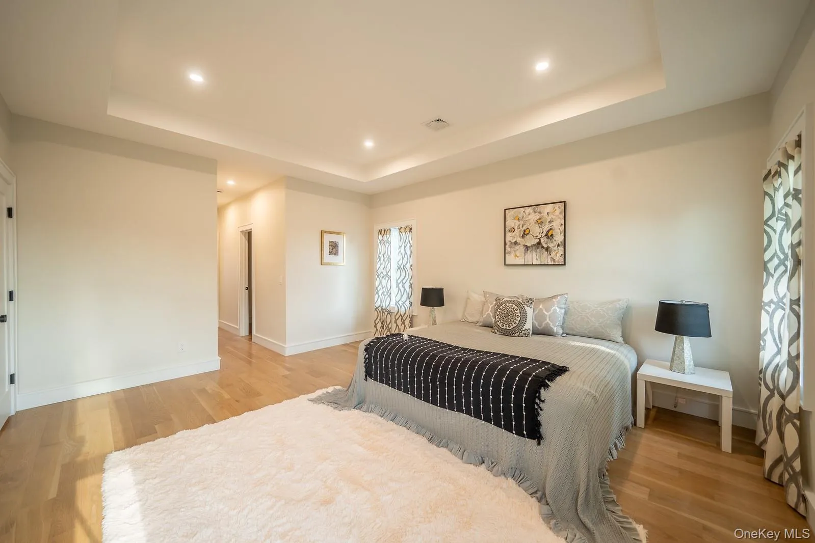 Bedroom with a raised ceiling, light wood-type flooring, and recessed lighting Bedroom with a raised ceiling, light wood-type flooring, and recessed lighting