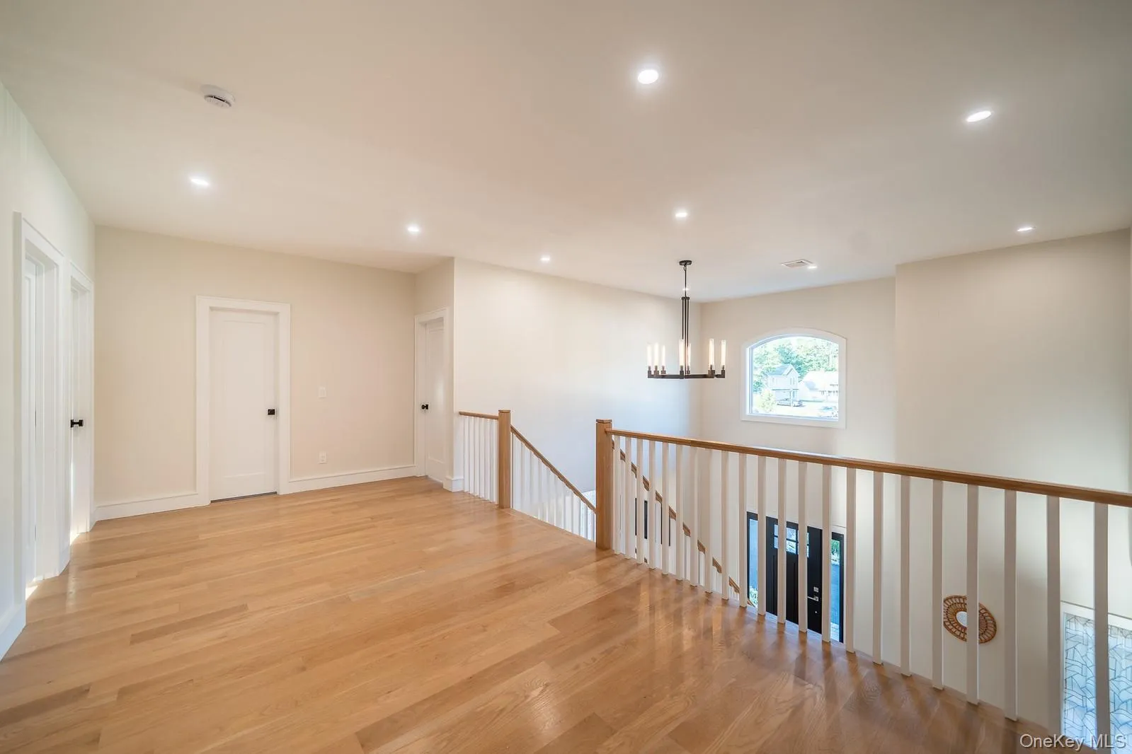 Hallway with light wood-style flooring, recessed lighting, a chandelier, and an upstairs landing Hallway with light wood-style flooring, recessed lighting, a chandelier, and an upstairs landing