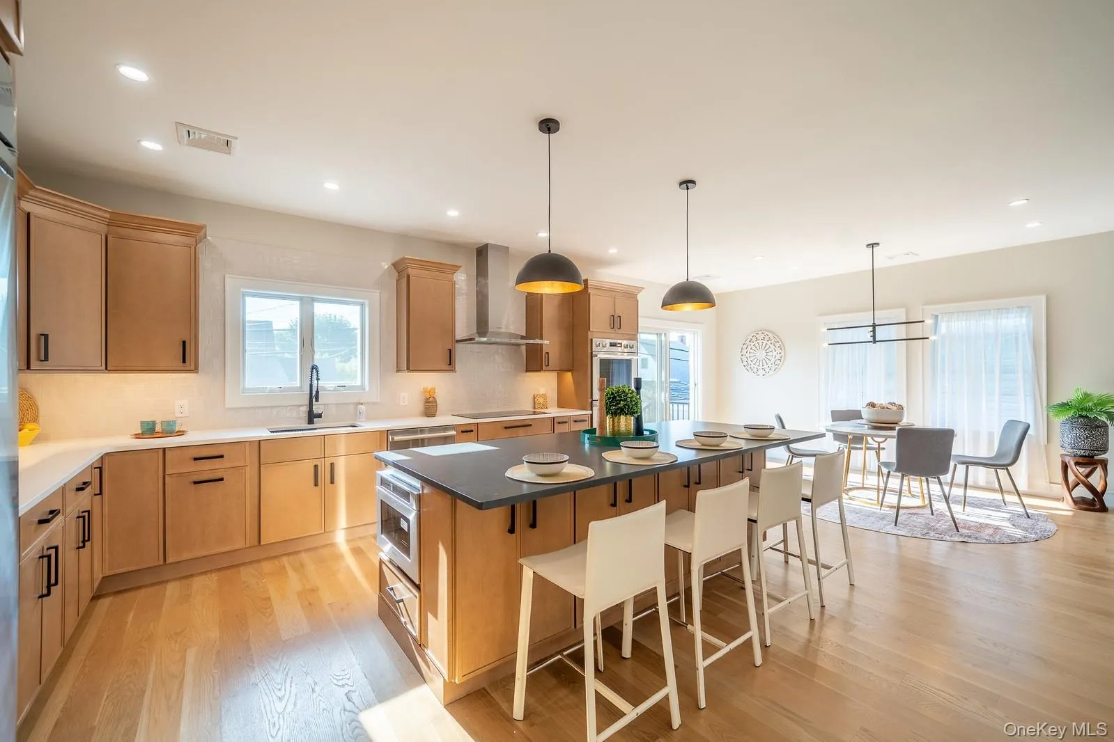 Kitchen featuring a kitchen breakfast bar, light wood-style floors, light brown cabinets, decorative backsplash, and recessed lighting Kitchen featuring a kitchen breakfast bar, light wood-style floors, light brown cabinets, decorative backsplash, and recessed lighting